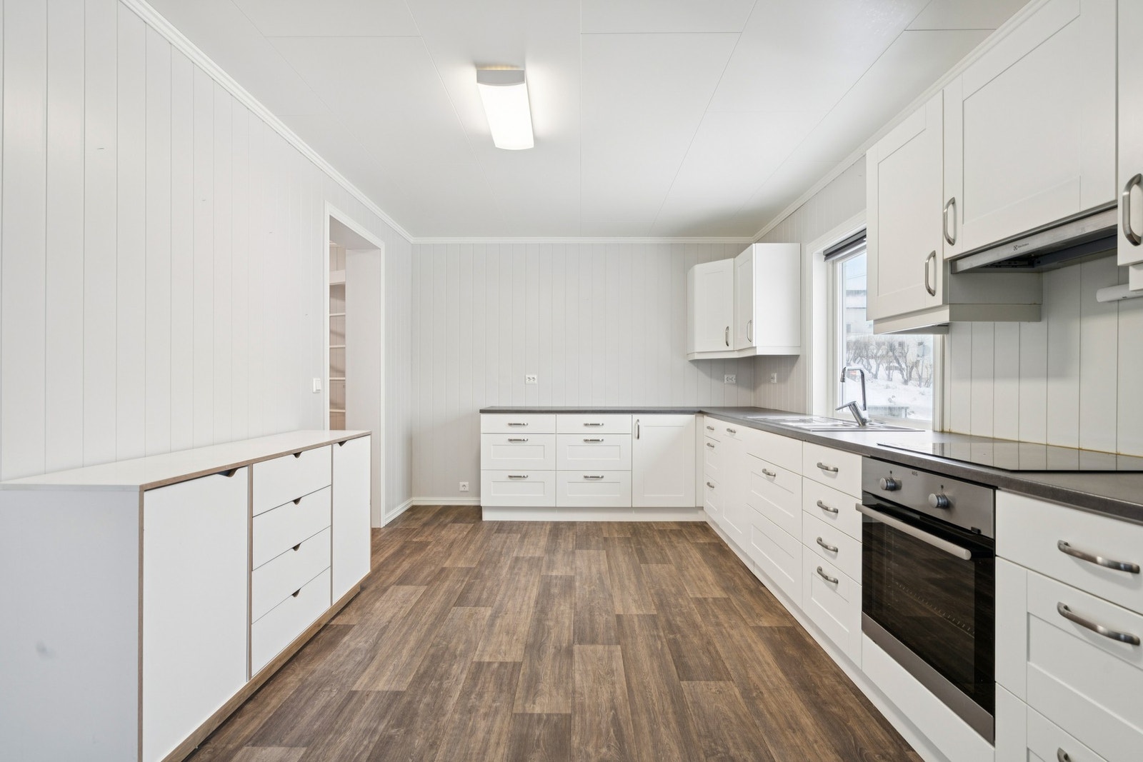 Kjøkkeninnredning med hvite, glatte fronter og slitesterk laminatbenkeplate. Galleribilde