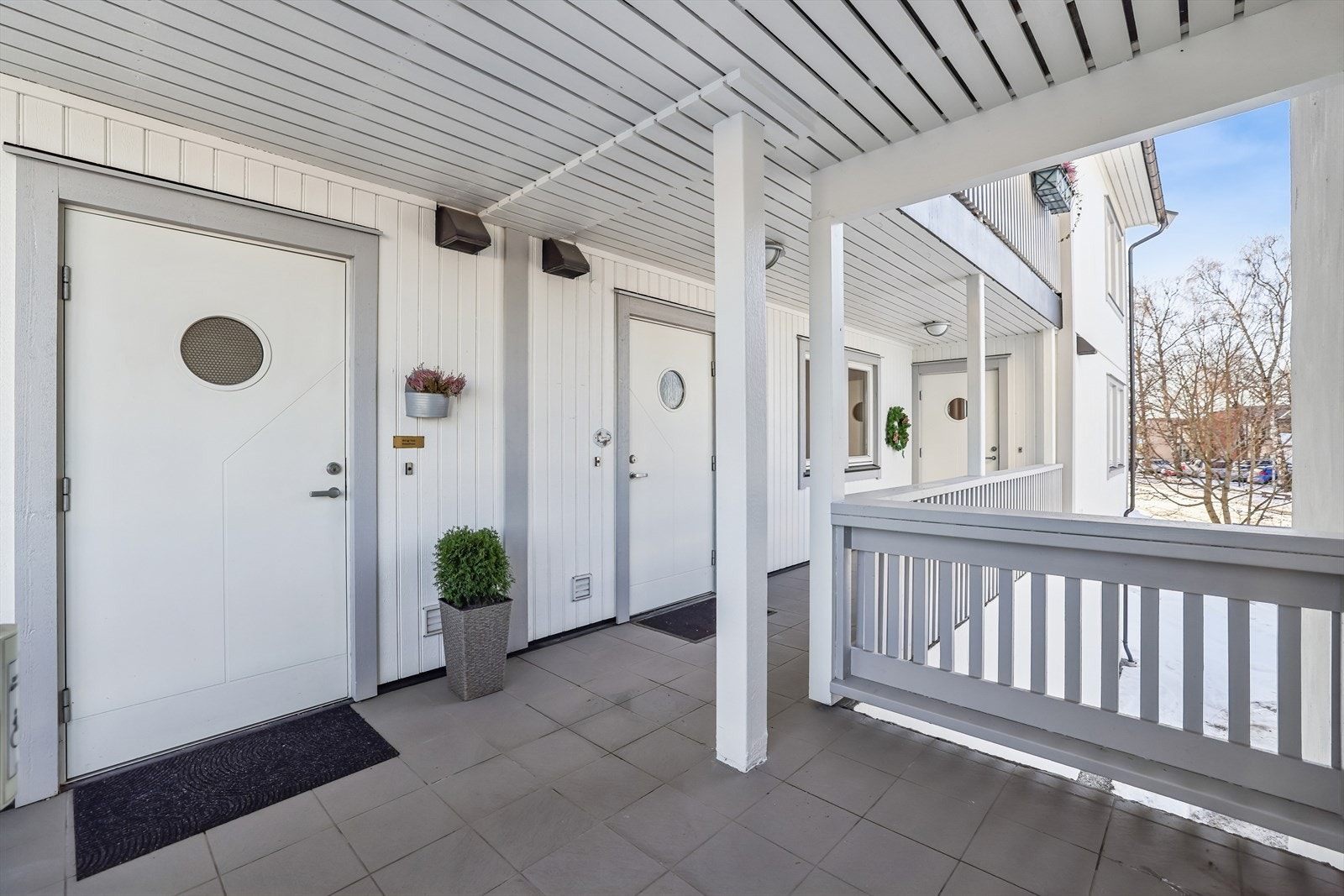Adkomst til leiligheten via en overbygget svalgang med flislagt gulv. Galleribilde