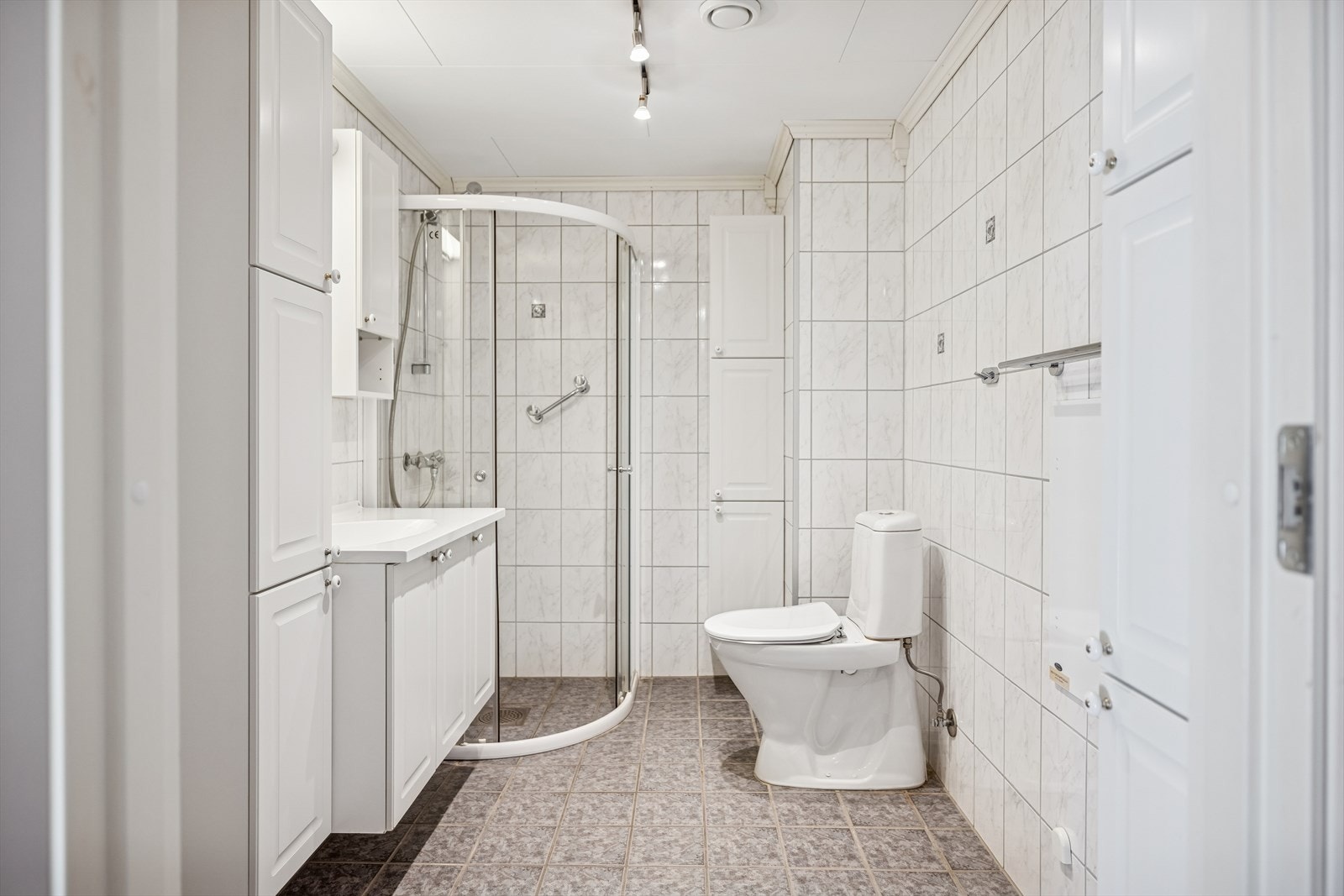 Her er det dusjhjørne med skyvedører, gulvmontert toalett og opplegg for vaskemaskin. Galleribilde