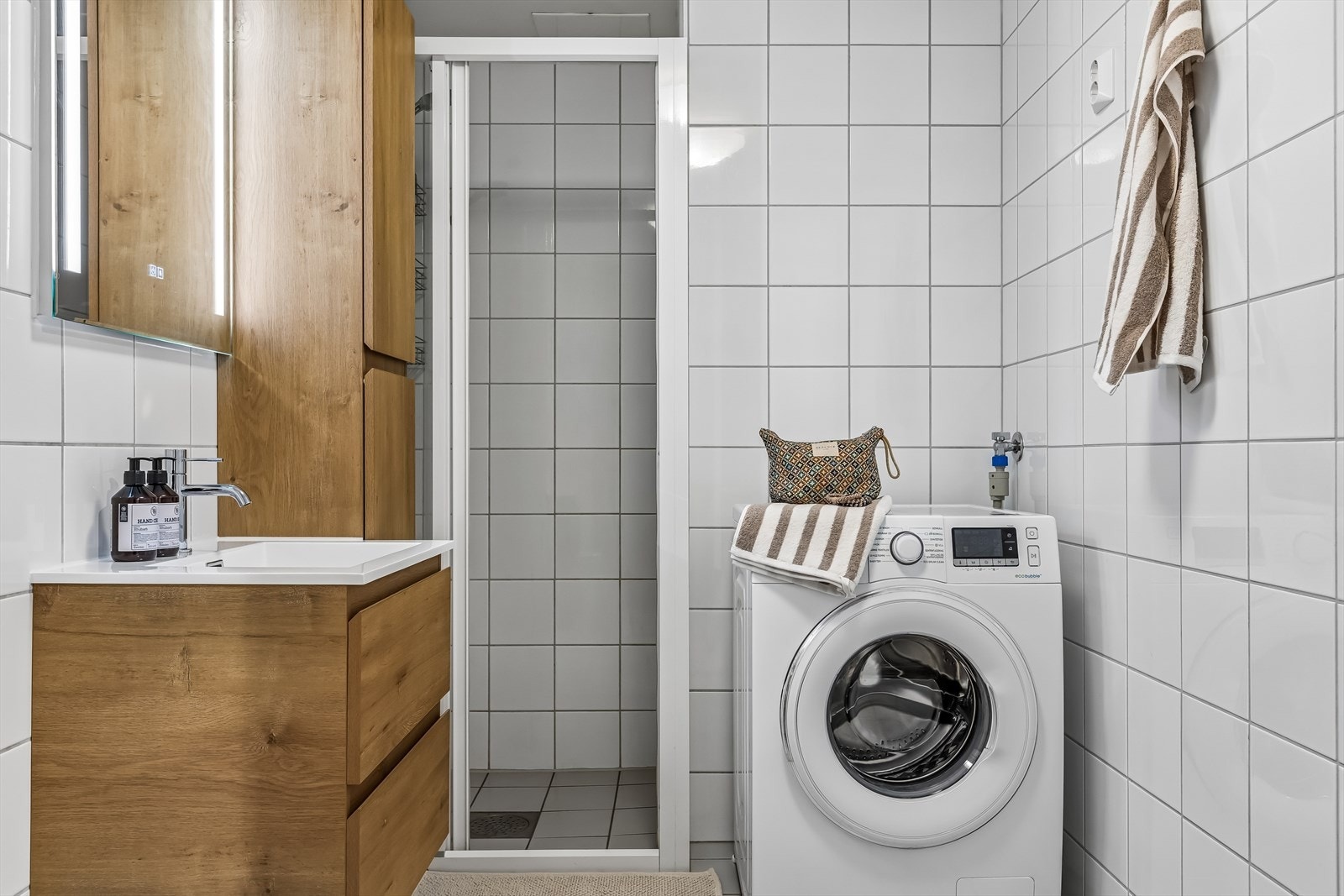 Badet er utstyrt med dusj, opplegg for vaskemaskin, veggmontert servant, skap og toalett. Badromsinnredning ble byttet i 2025. Galleribilde