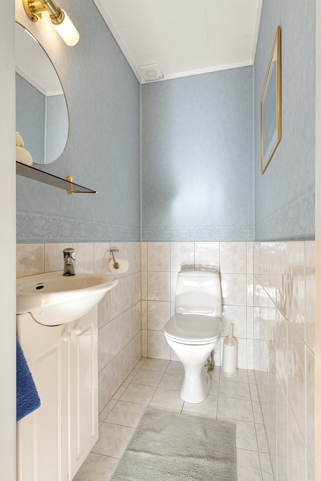 Separat toalettrom med gulvstående toalett og vegghengt servant med skapinnredning under. Galleribilde