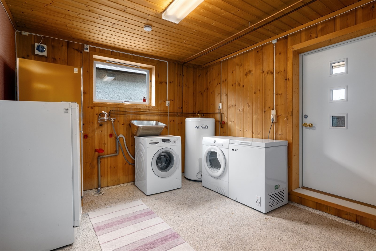 Eldre vaskerom innredet med opplegg for vaskemaskin og utslagsvask. Fra vaskerommet er det utgang til gårdsplassen. Galleribilde