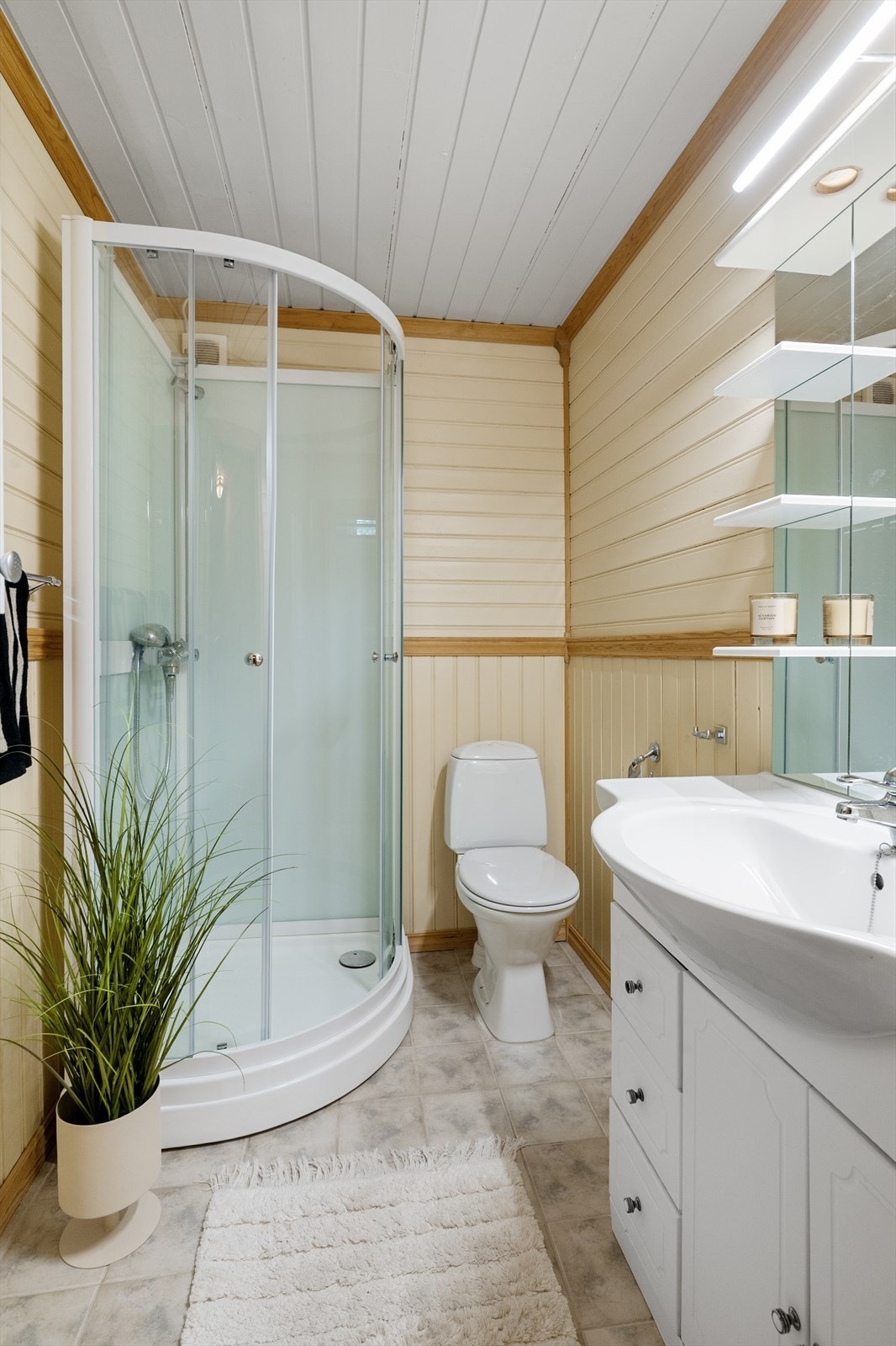 Eldre bad innredet med servantskap, toalett og dusjkabinett. Galleribilde