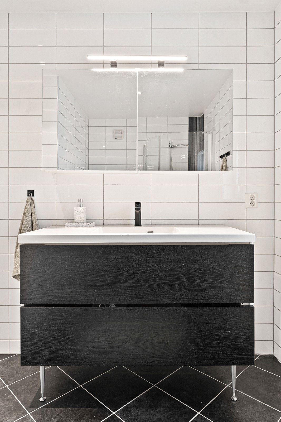 Badet er innredet med baderomsinnredning, overskap med speil, vegghengt toalett, samt dusjhjørne med to glassdører. Galleribilde