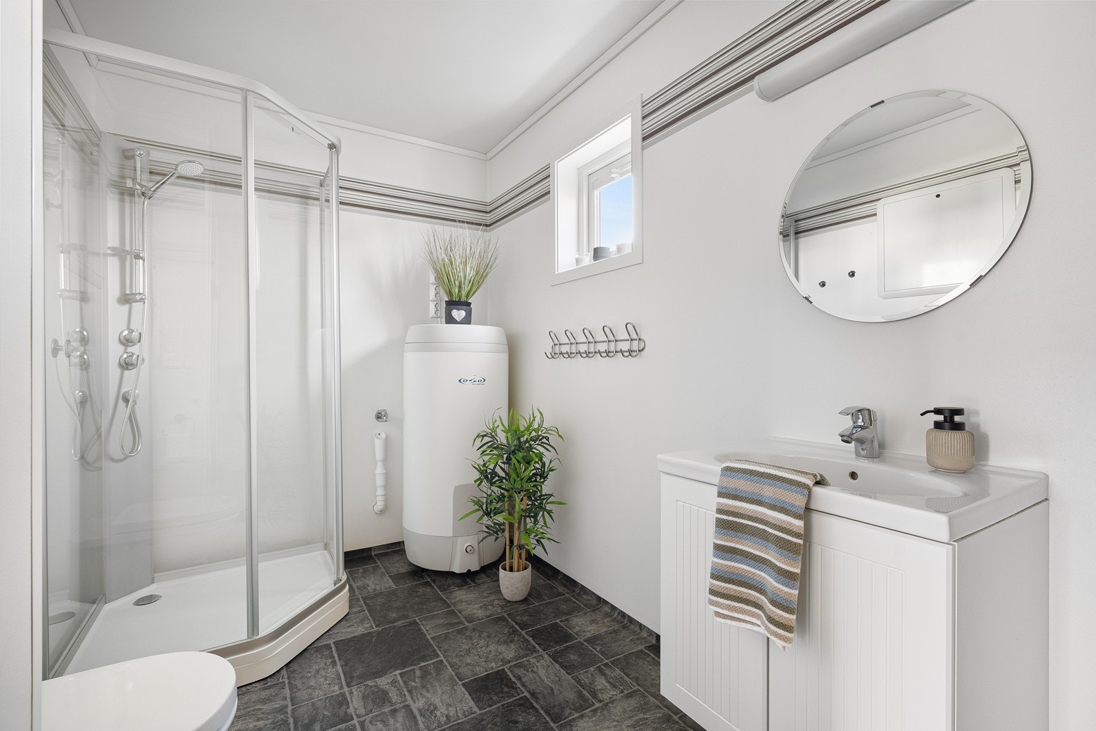 Bad i første etasje utstyrt med vask i servant, vegghengt toalett og dusjkabinett. Galleribilde