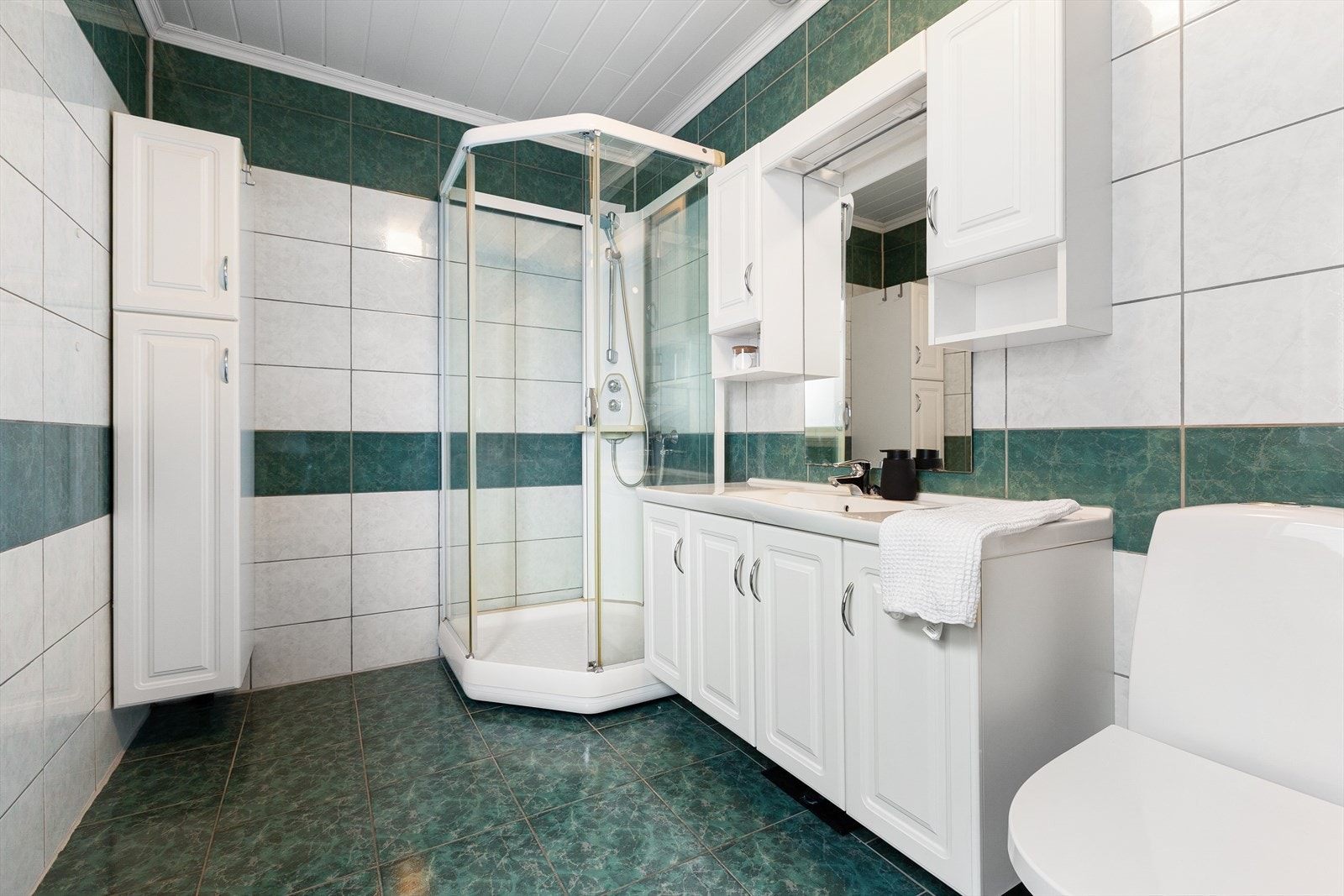 Romslig bad med dusj, servant og wc. Her er det fliser på vegg og gulv. Galleribilde