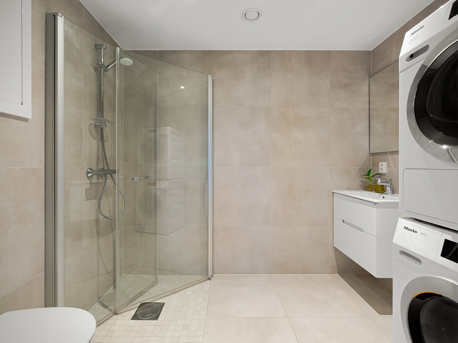 Ellers består innredningen av vegghengt toalett, dusjhjørne, servantskap og opplegg til vaskemaskin. Galleribilde