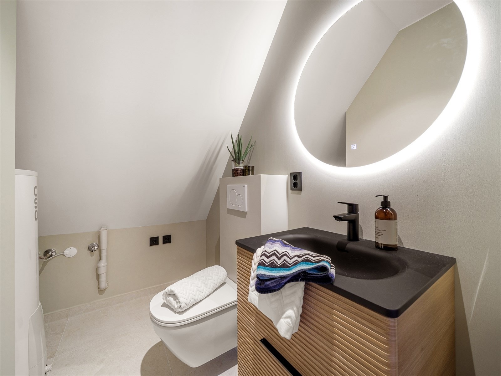 Toalettrommet er pent innredet med servant med nedfelt vask, veggmontert toalett og opplegg for vaskemaskin. Galleribilde