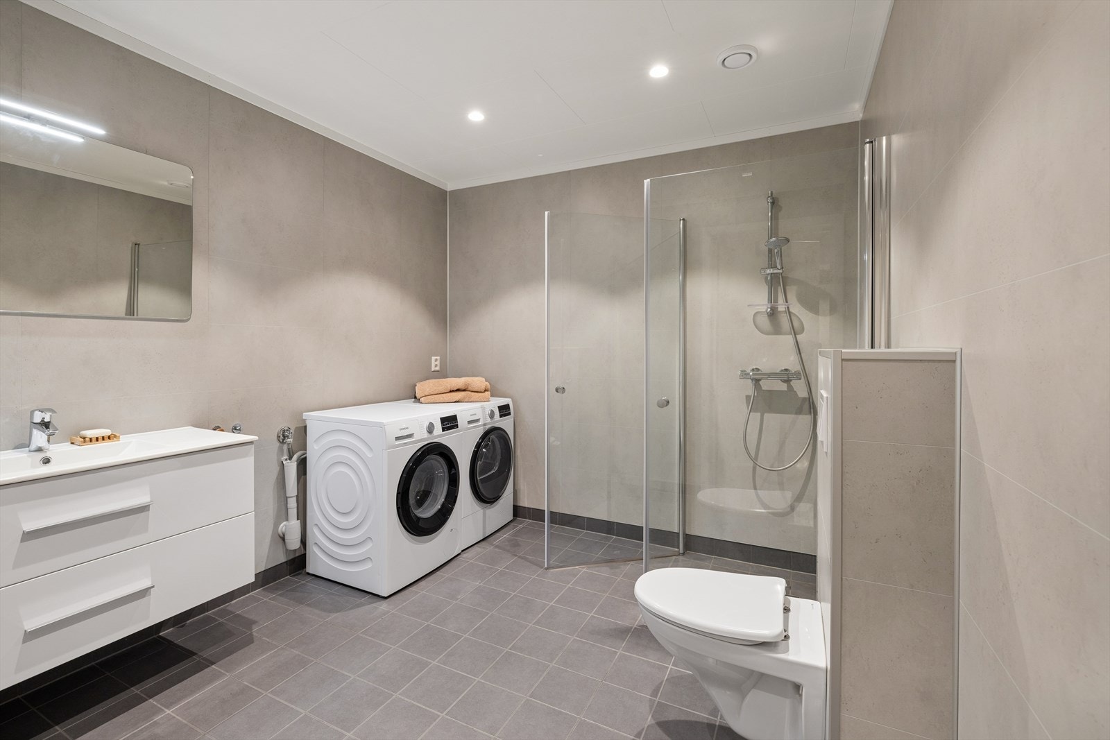 Pent bad med baderomsplater på veggene og fliser på gulv med gulvvarme. Galleribilde