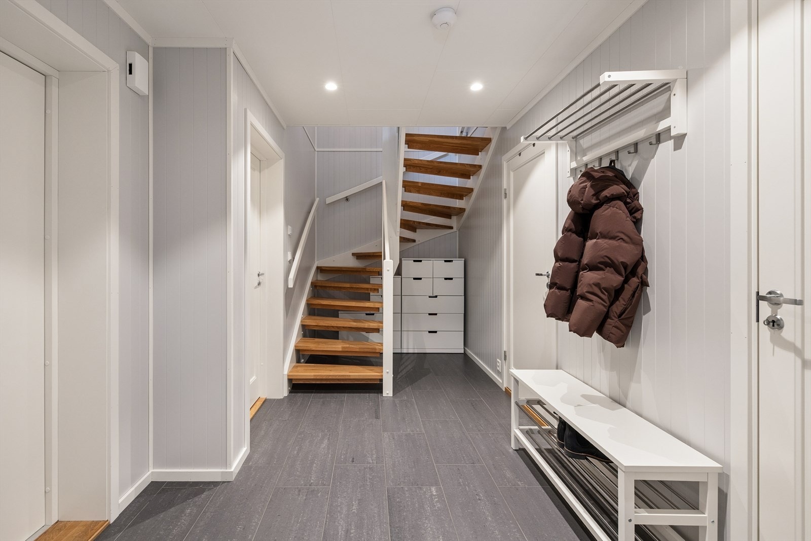 Det første som møter deg når du kommer inn er en entré/gang med plass til å sette fra seg sko og henge opp yttertøy. Her er det fliser på gulv med gulvvarme og downlights i tak. Fra gangen er det også adkomst til en praktisk bod/teknisk rom. Galleribilde