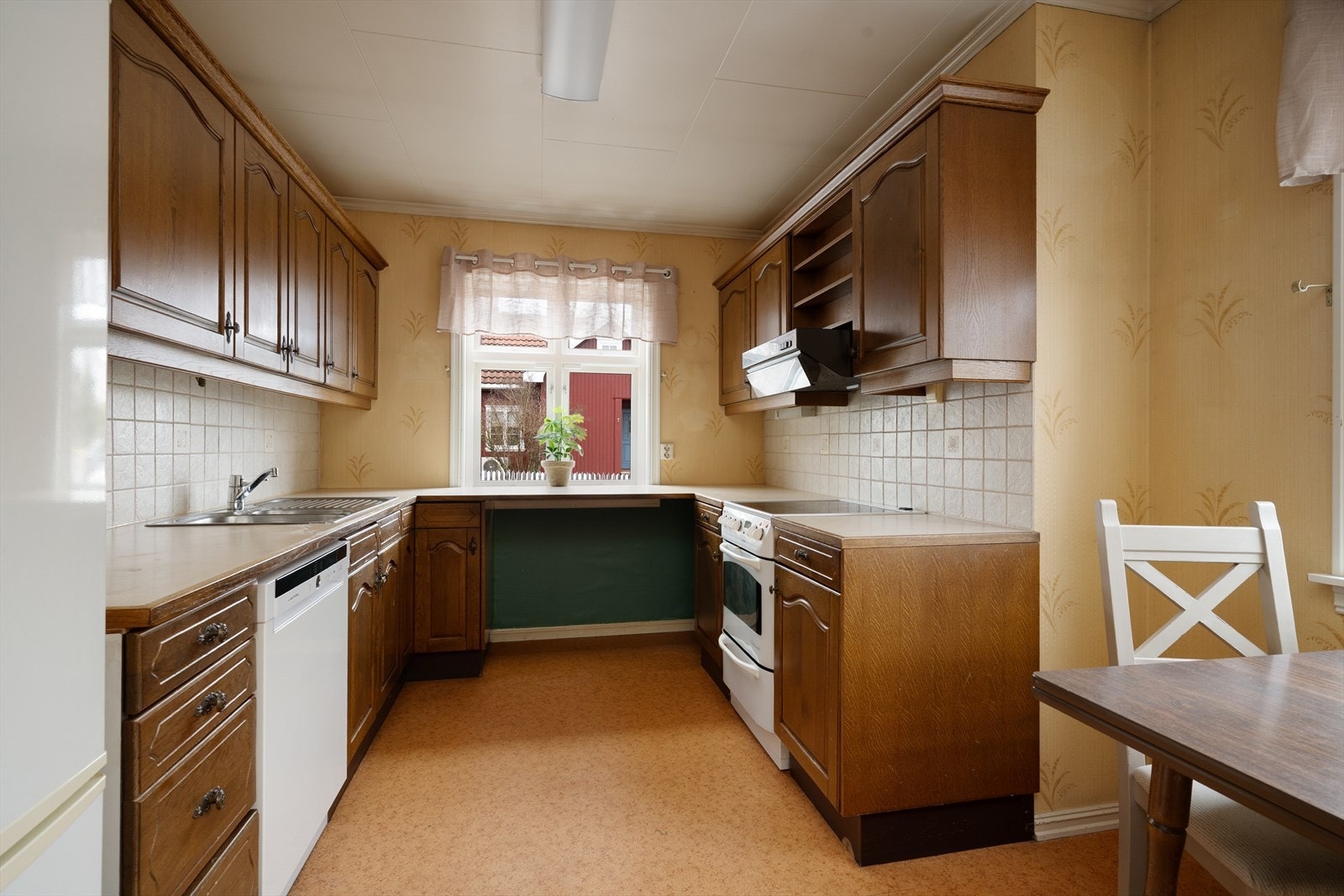 Eldre innredning med god oppbevaringsplass, hvor det er avsatt plass til frittstående oppvaskmaskin, komfyr og kjøl/fryseskap. Over kokesonen er det ventilator med avtrekk ut. Galleribilde