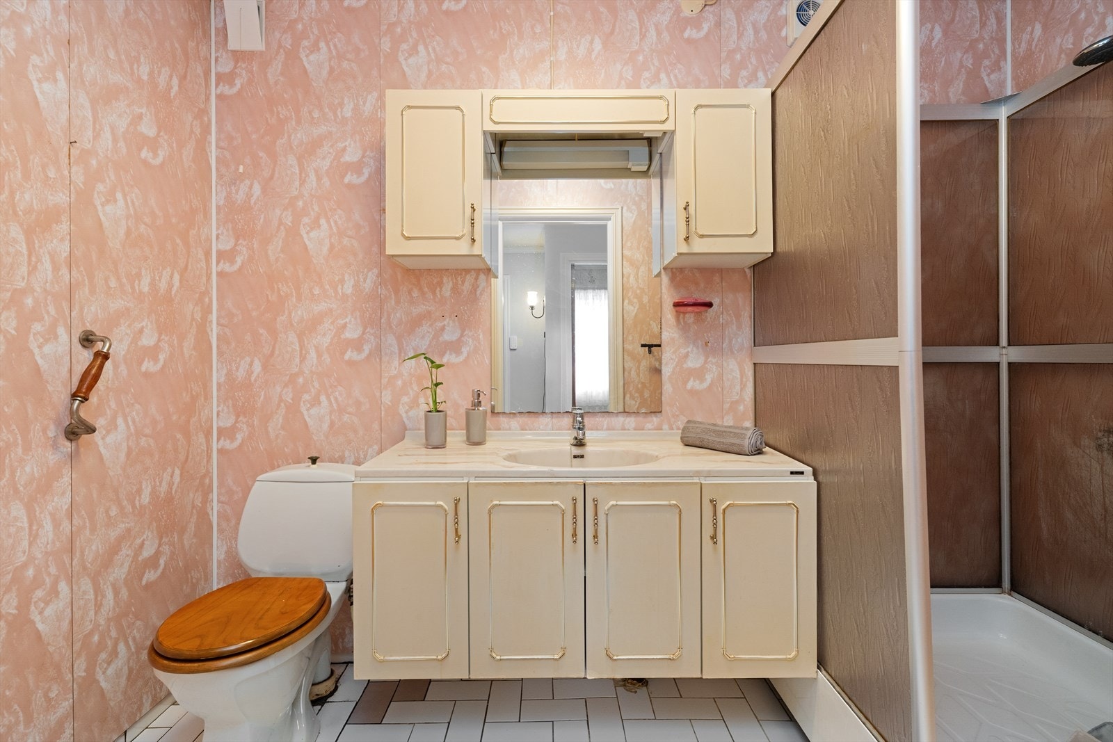 Hybelen har et eldre baderom som er innredet med baderomsinnredning, dusjkabinett og toalett. Galleribilde