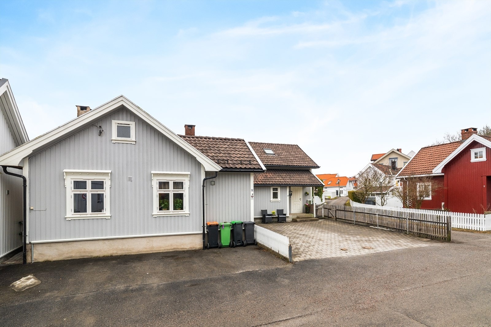 Biloppstillingsplasser på gårdsplass med belegningsstein og asfalt i forkant av boligen. Galleribilde