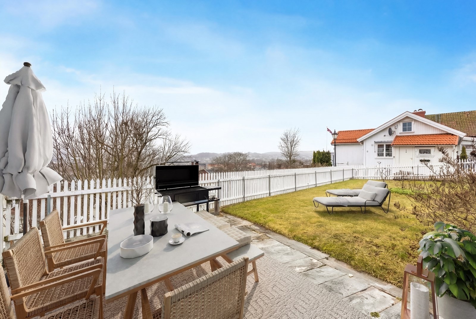 Eiendommen har også en hellelagt platting nederst i hagen hvor man kan nyte varme sommerdager. (Digital møblering, kun en illustrasjon) Galleribilde