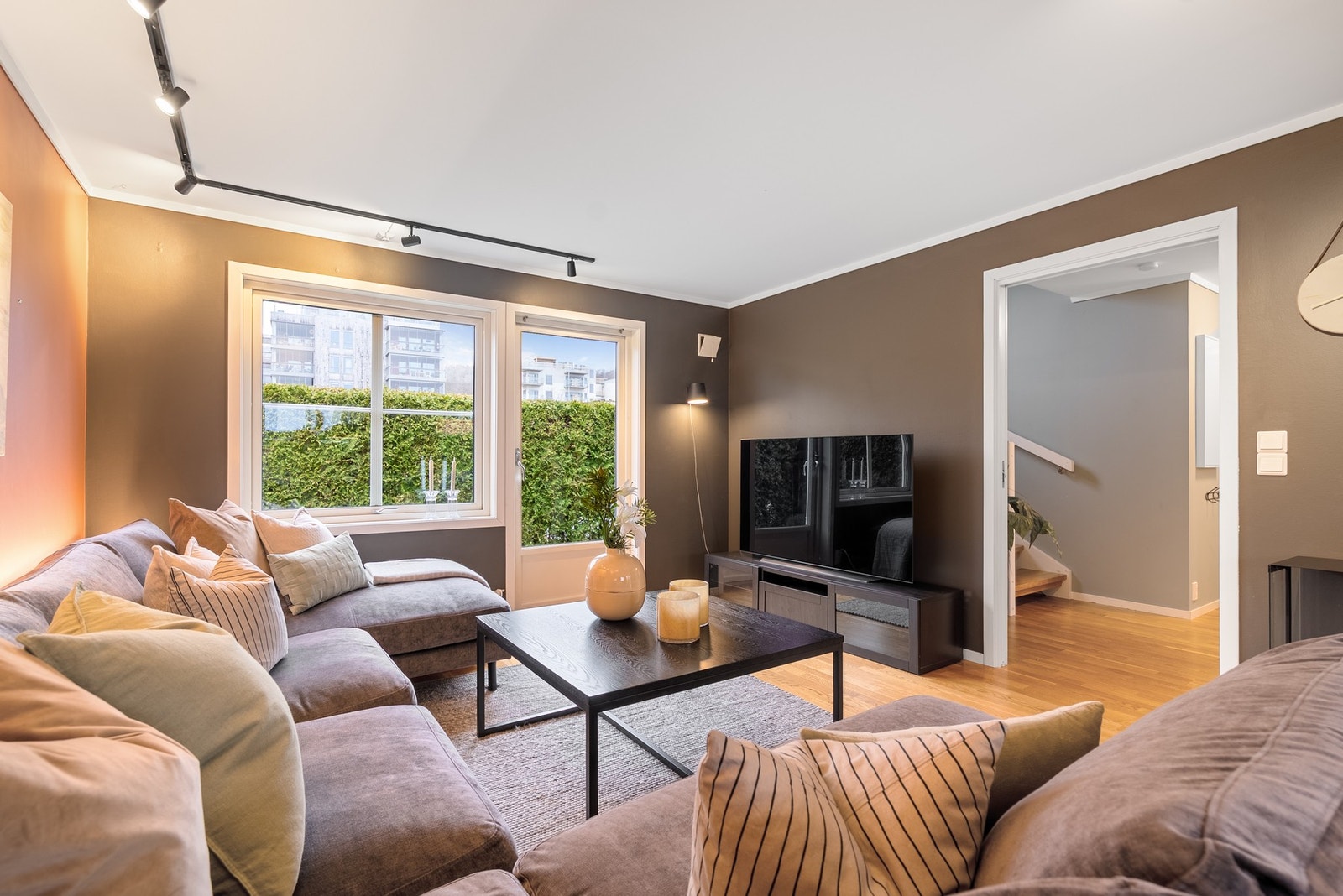 Store vindusflater og spotskinner kombinert med jordtoner på veggene gir et lyst og innbydende rom som enkelt kan møbleres og tilpasses din egen stil Galleribilde