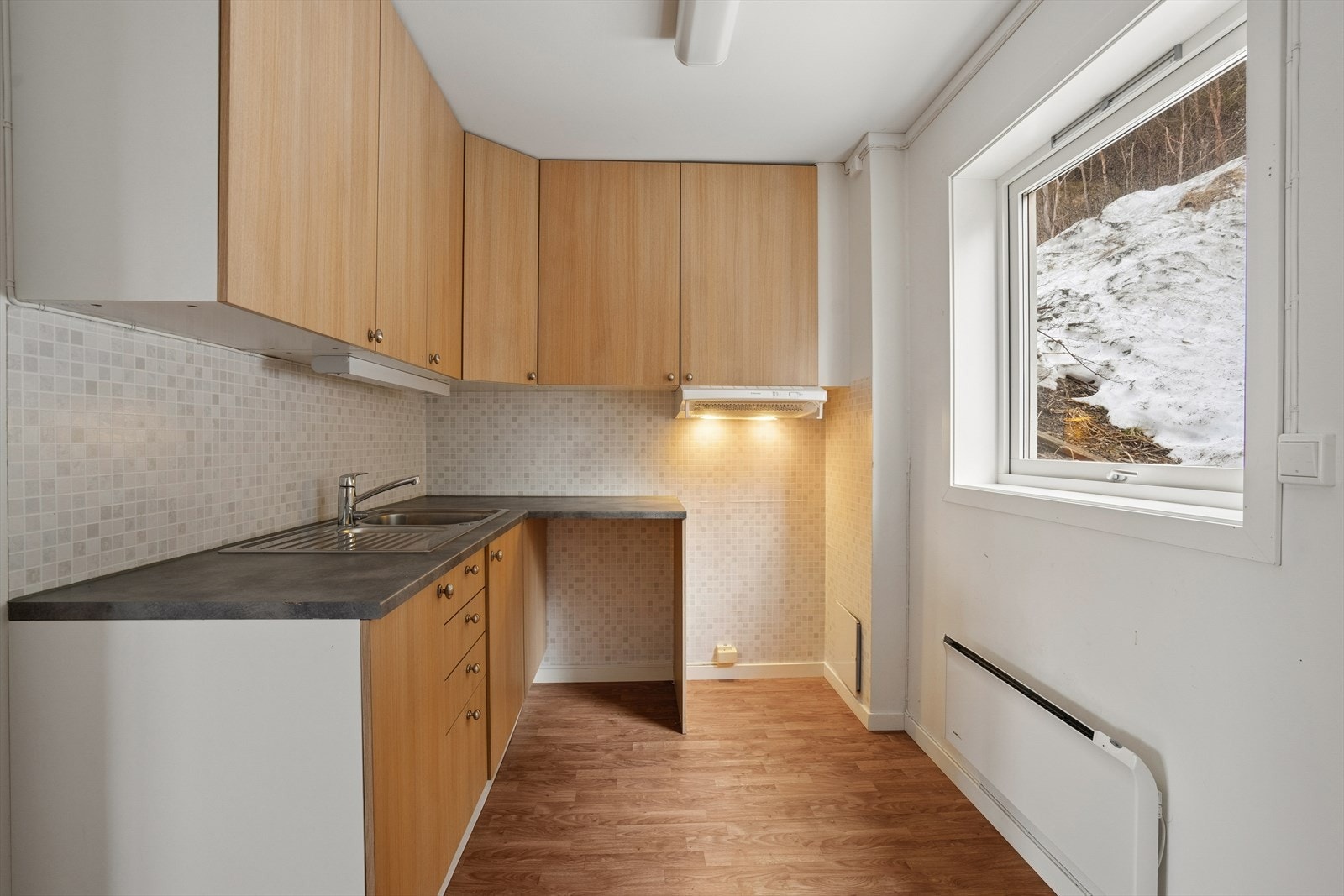 Kjøkkenet har en innredning med glatte fronter og benkeplate i laminat, som gir et lettstelt uttrykk Galleribilde