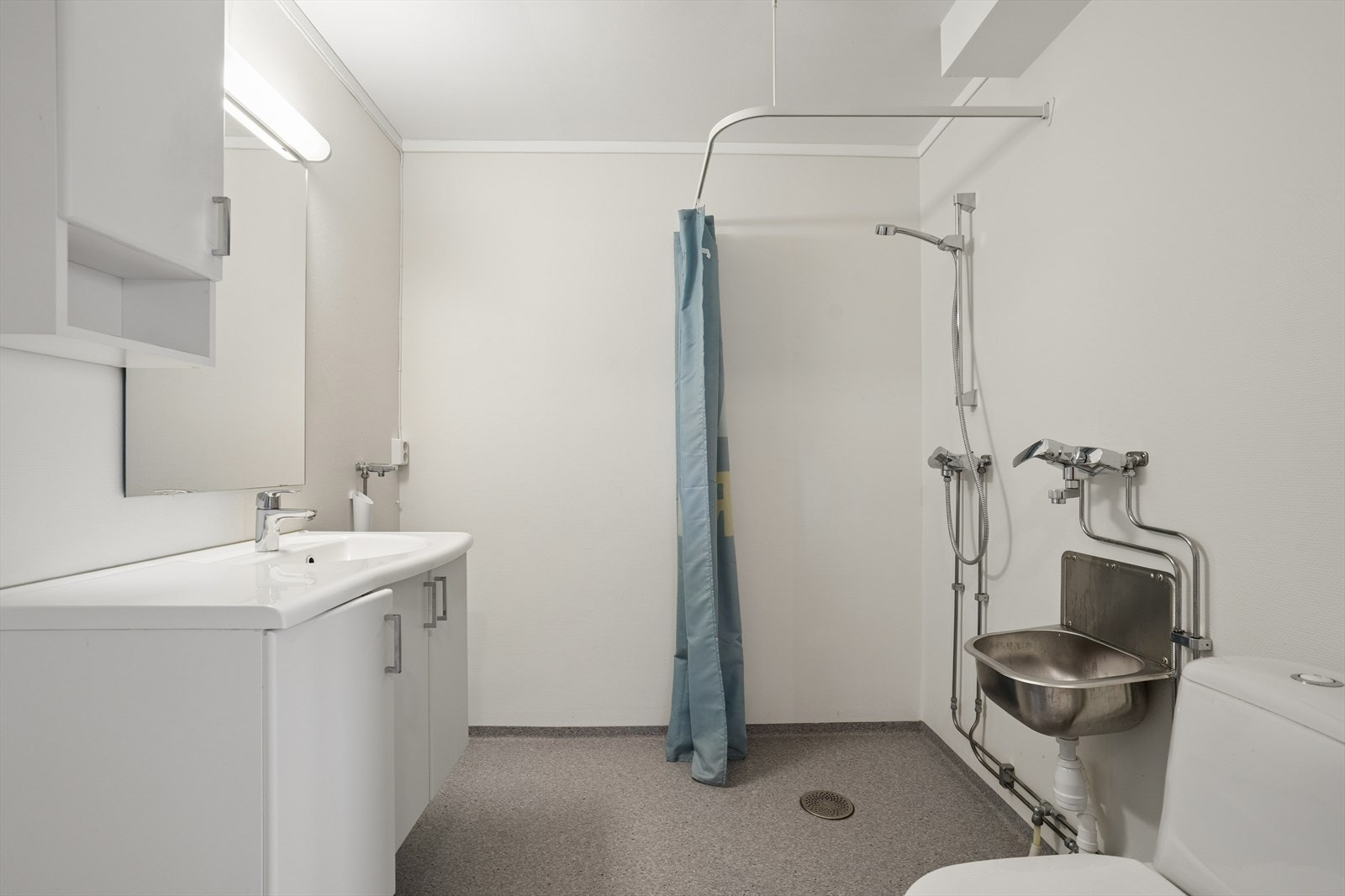 Rommet er utstyrt med baderomsinnredning med nedfelt servant, gulvstående toalett og et praktisk dusjhjørne. I tillegg er det opplegg for vaskemaskin samt en utslagsvask i stål Galleribilde
