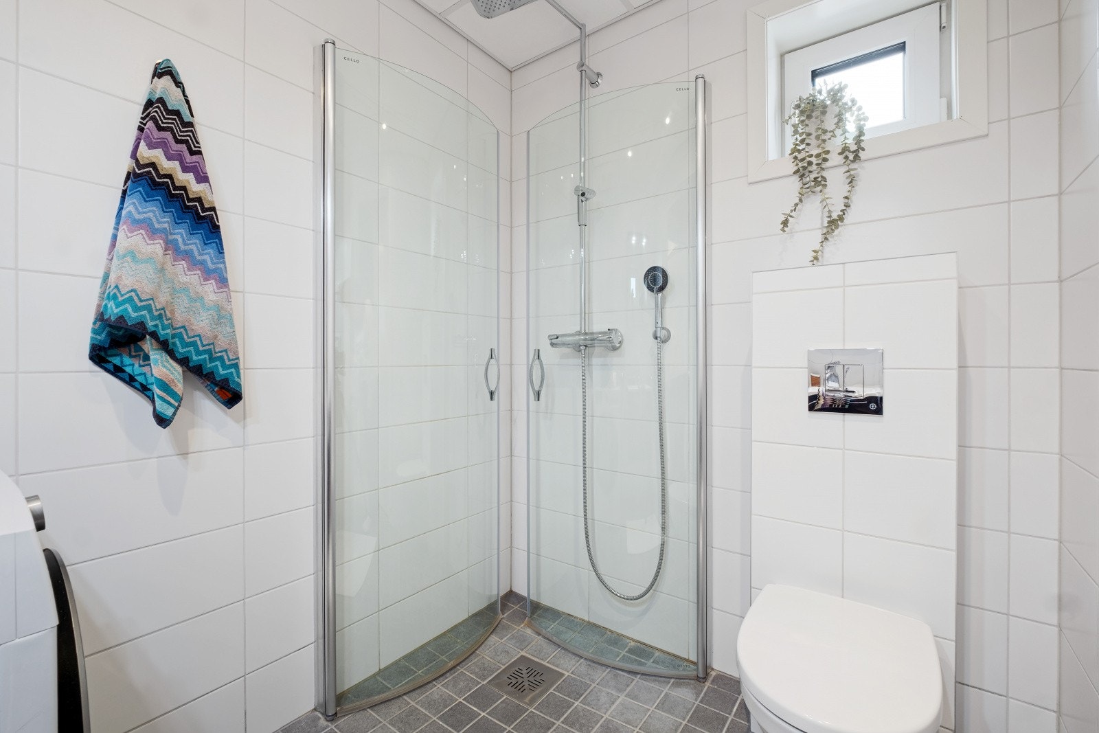 Her finner du vegghengt toalett, dusjhjørne med innfellbare glassvegger, baderomsinnredning og opplegg for vaskemaskin Galleribilde