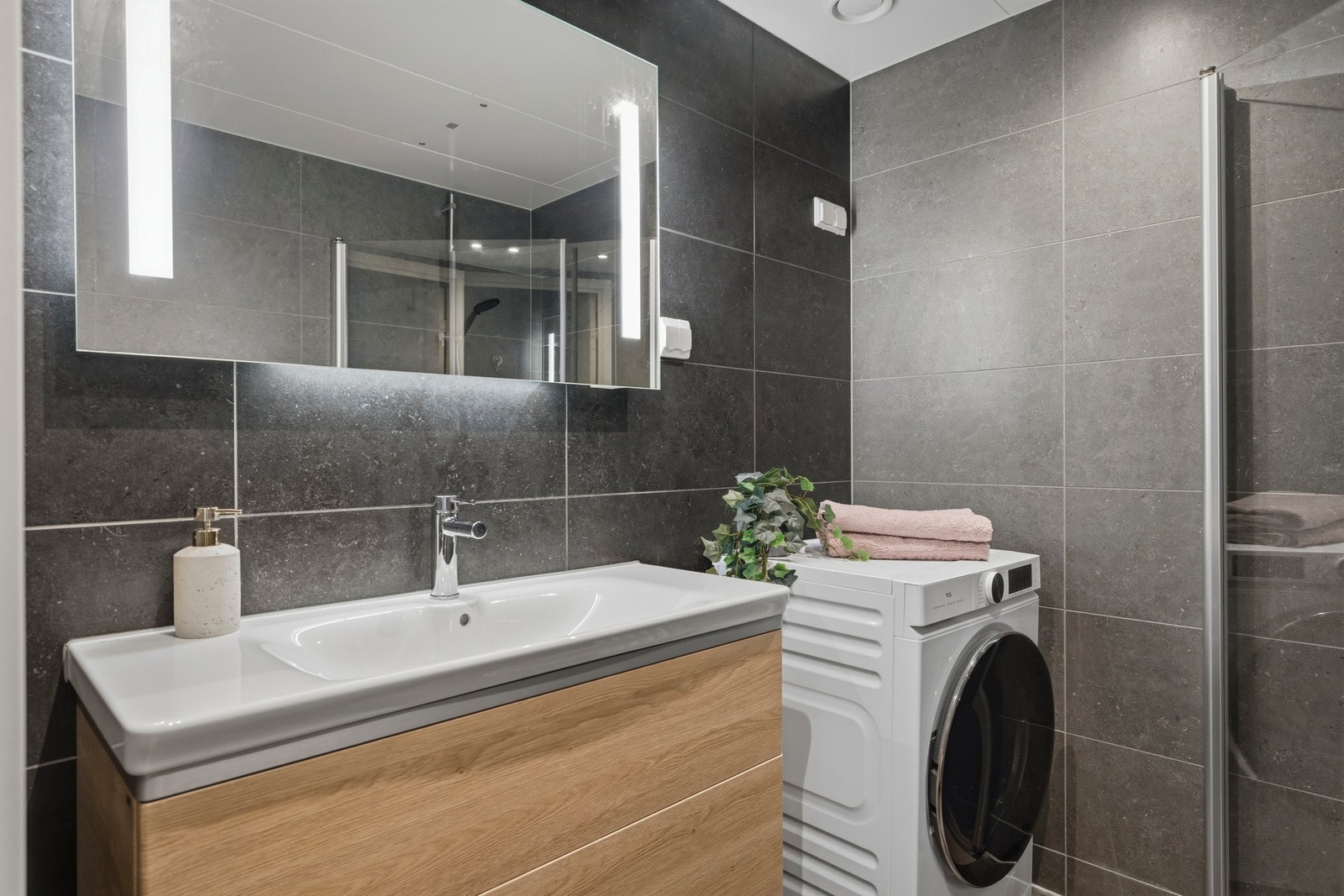 Servantskap med glatte fronter og heldekkende servant.
Speil med lysarmatur på vegg over servant. Galleribilde