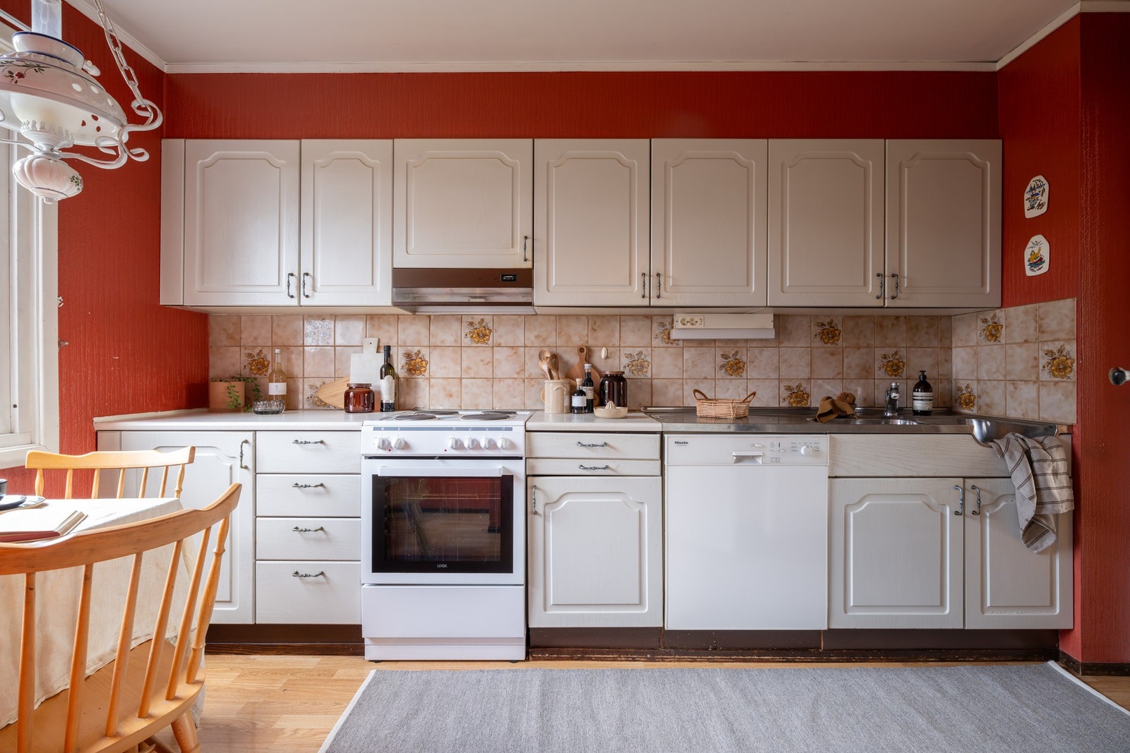 Innredningen har profilerte fronter, laminert benkeplate og benkeplate av rustfritt stål med nedfelt oppvaskkum, samt fliser mellom benkeplate og overskap. Galleribilde