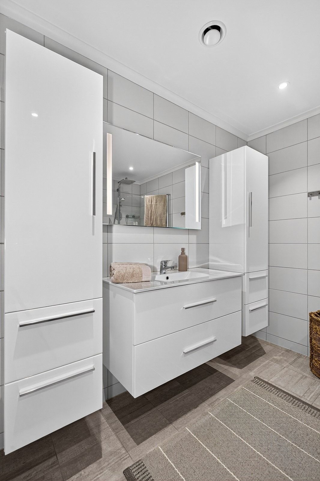 Innredningen har heldekkende hvit vask, underskuffer med slette fronter og speil med lys. I tillegg to høyskap med ekstra oppbevaringsplass. Galleribilde