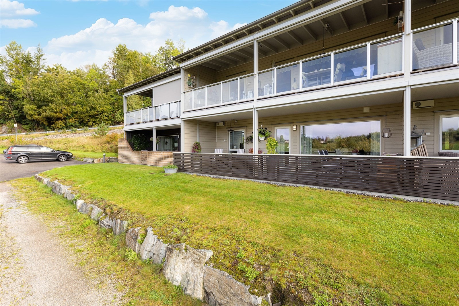 Fra borettslagets felles gressplen er det port inn til boligens veranda. Galleribilde