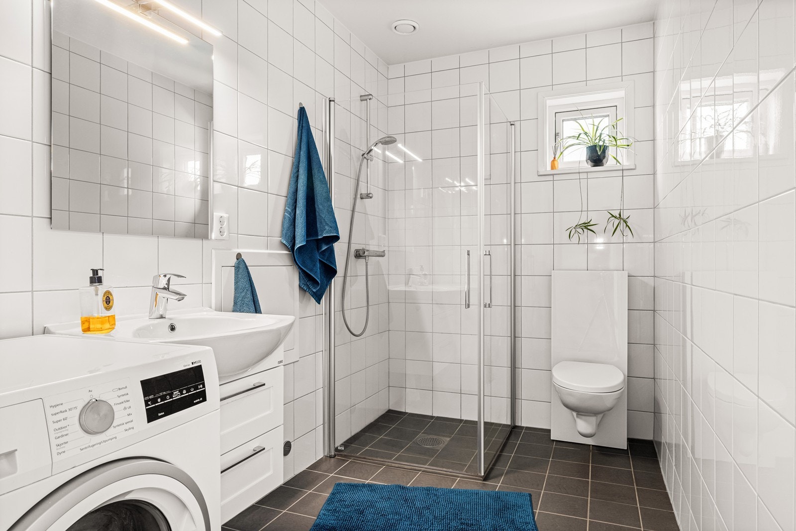 Helfliset bad med elektriske varmekabler i gulvet, vegghengt toalett og opplegg for vaskemaskin. Galleribilde