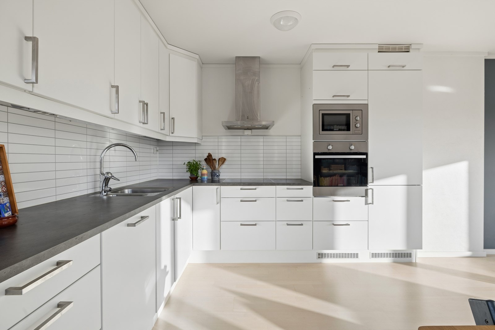 Kjøkkenet fra 2018 har en funksjonell utforming. Lys, pen innredning med slette fronter og laminat benkeplate. Kitchenboard på veggen. Galleribilde