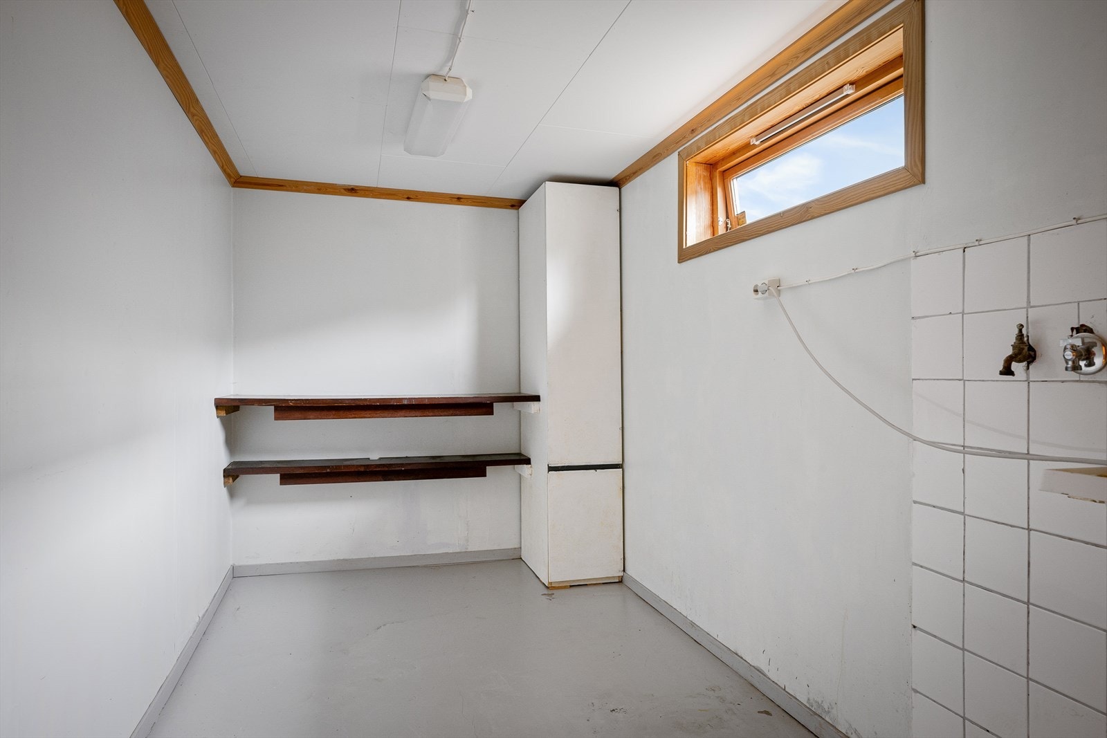 Vaskerom i kjelleren med utslagsvask og opplegg for vaskemaskin. Galleribilde