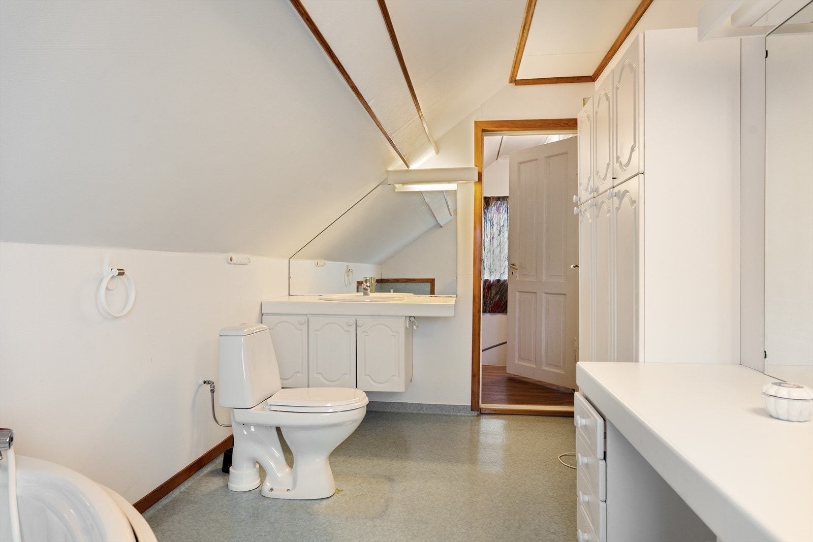 Badet er innredet med hvit baderomsinnredning, gulvstående toalett og boblebadekar Galleribilde