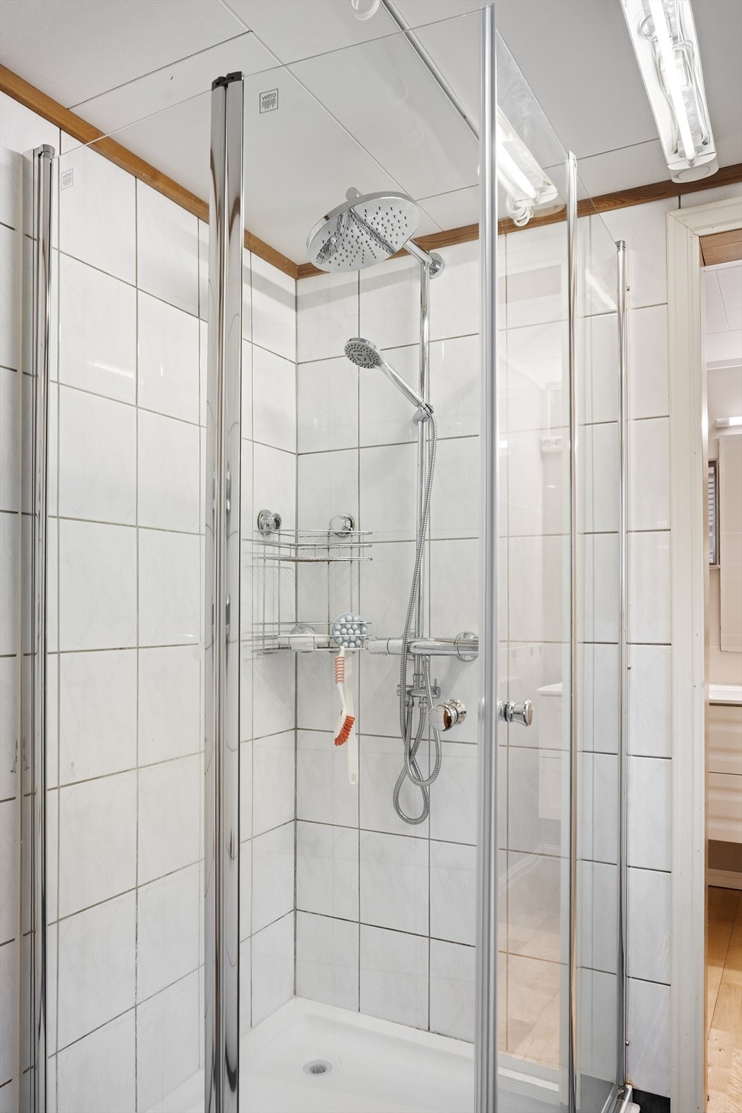 Badet er innredet med hvit baderomsinnredning, gulvstående toalett og dusjkabinett Galleribilde