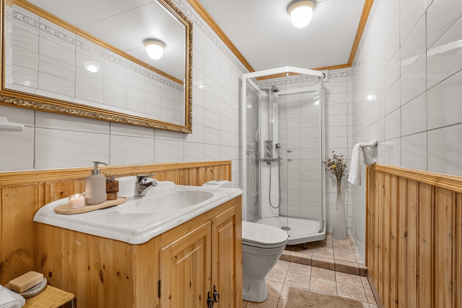 Badet i underetasjen har flislagte gulv og vegger kombinert med panel, samt elektriske varmekabler for komfort. Galleribilde