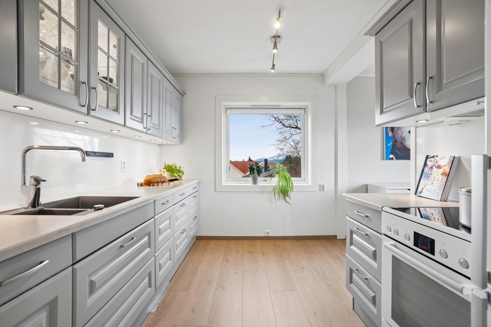 Kjøkkeninnredningen har profilerte fronter med benkeplate i laminat. Det er montert kitchenboard-plater over kjøkkenbenk. Alle hvitevarene på kjøkkenet medfølger. Galleribilde