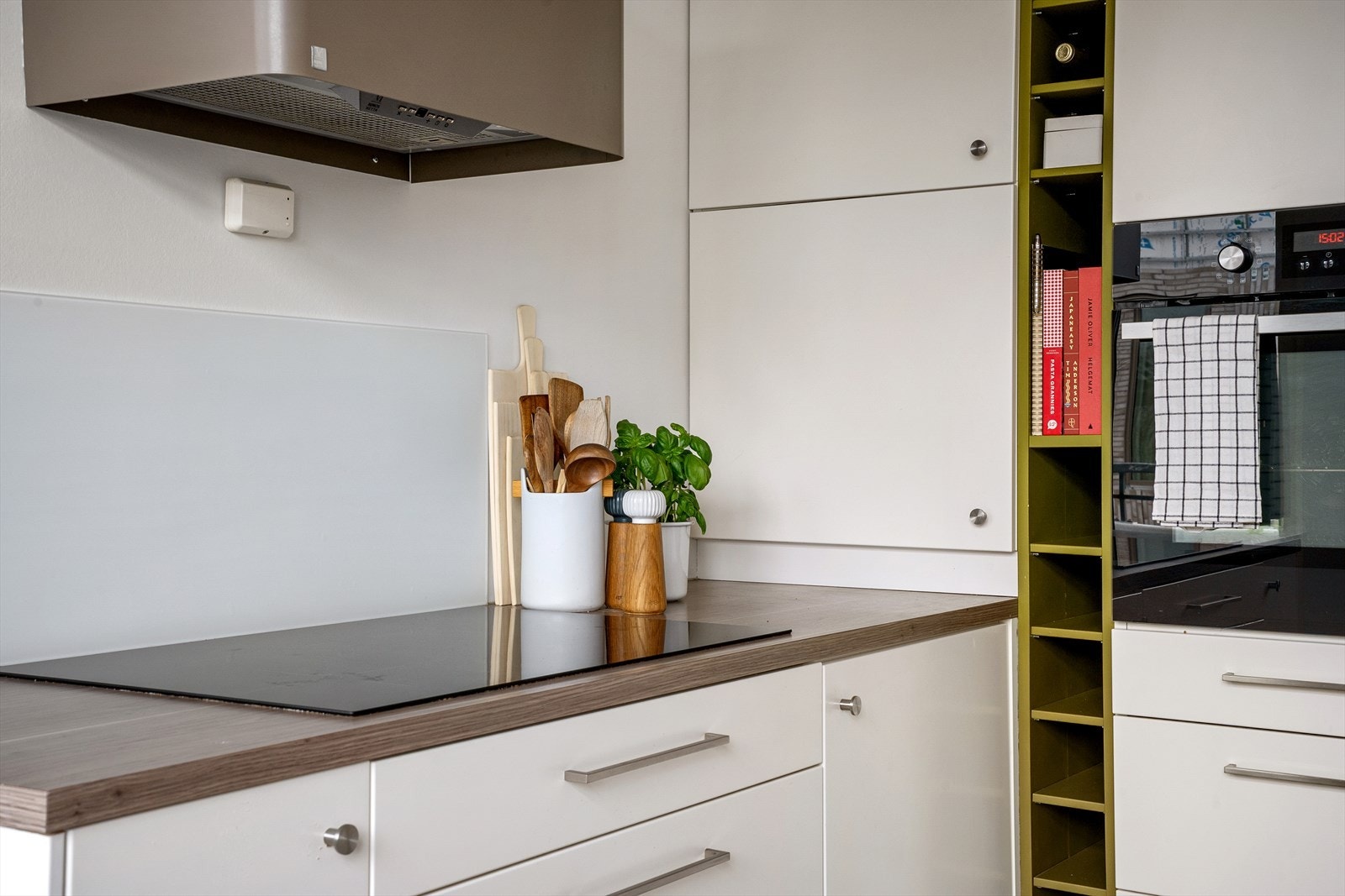 Delikat designvifte bryter fint med de lyse frontene og skaper varme. Optimalt plasserte arbeidssoner og hvitevarer for funksjonalitet. Galleribilde