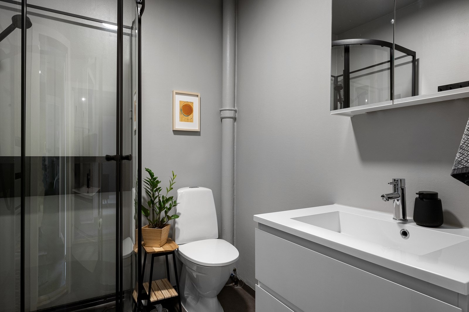 Badet fremstår også med moderne innredning og god plass. Godt med oppbevaring i både speilskap og seksjon, samt plass for ekstra skap og hyller. Tett dusjkabinett med sorte detaljer gir moderne og trygge forhold. Galleribilde