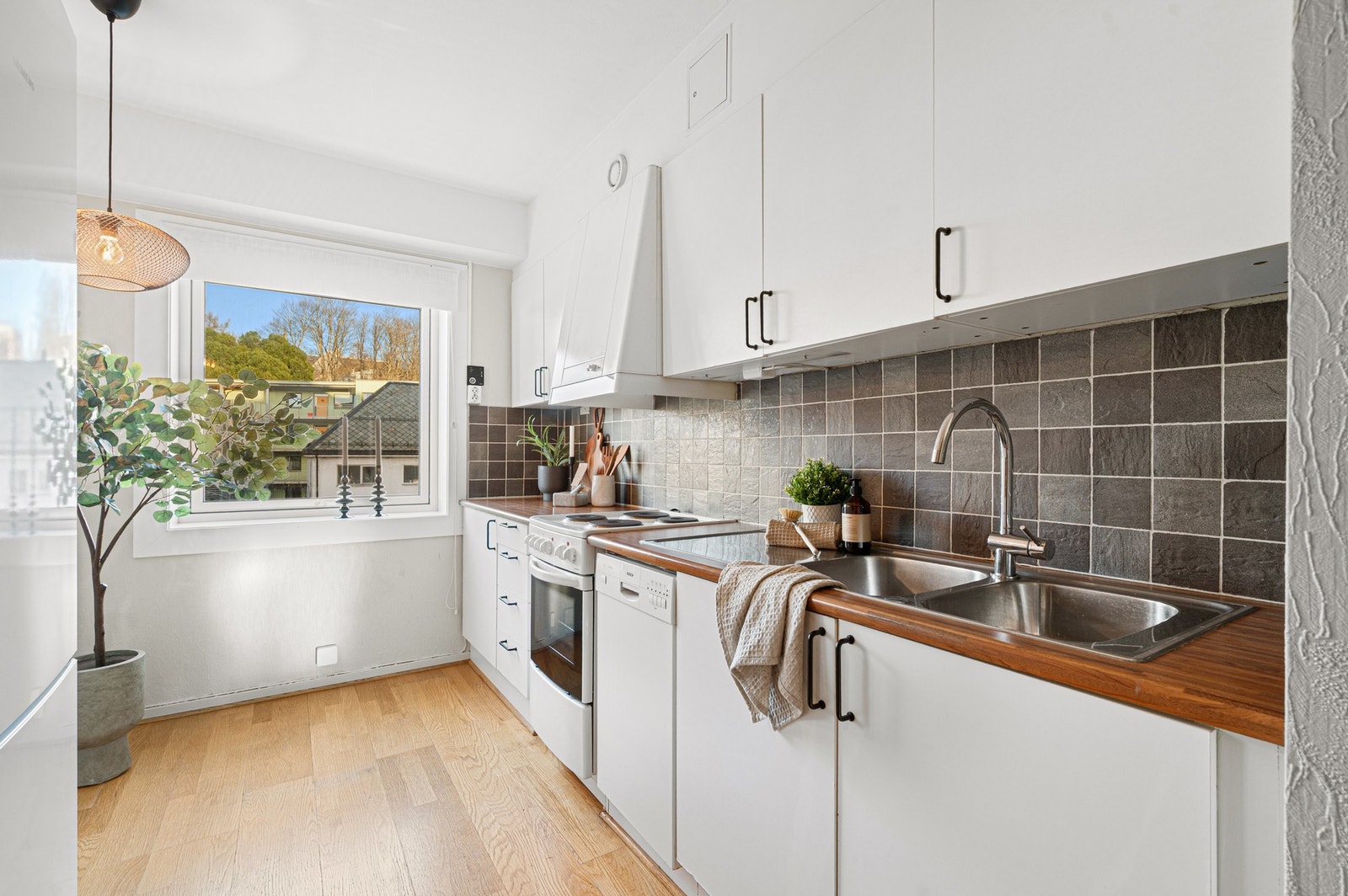 Lyst og velfungerende kjøkken med integrerte hvitevarer. Galleribilde