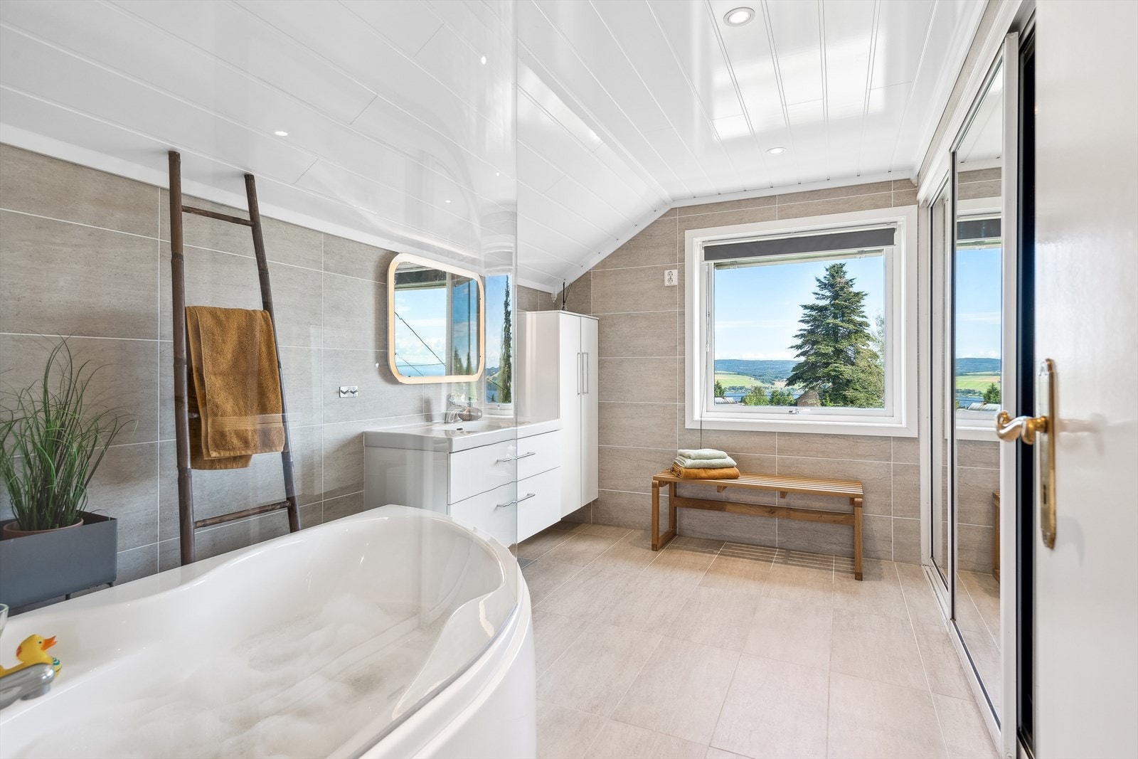 Her er det badekar med dusj, baderomsinnredning med servant og skyvedørsgarderobe med speildører. Galleribilde