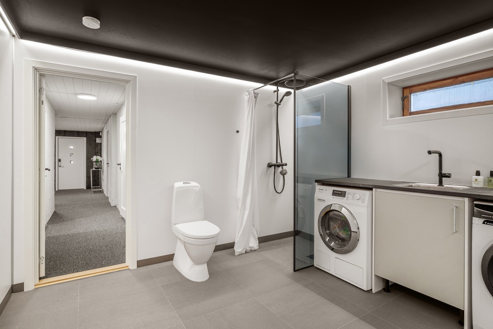 Stor baderom i kjeller utstyrt med dusjnisje med regnfallsdusj, håndholdt dusj og gulvstående klosett. Galleribilde