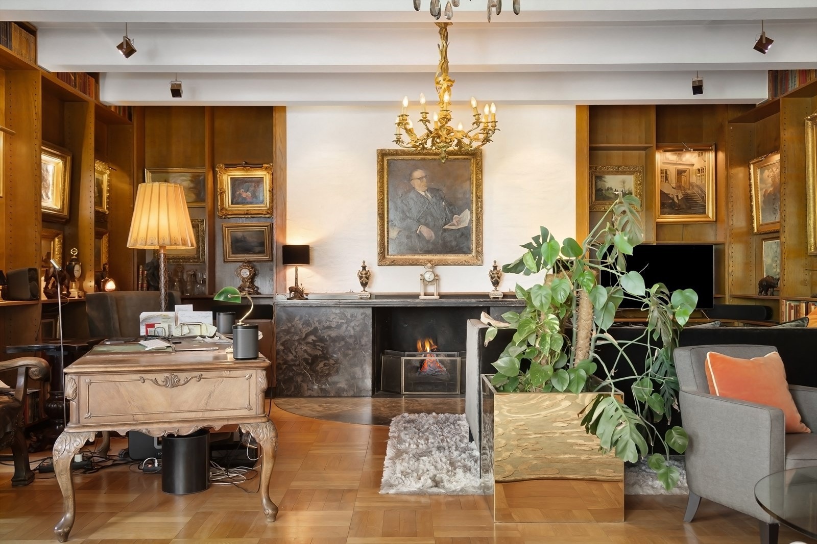 Bibliotek/stue har stor peis som er omrammet av innfelte bokhyller Galleribilde