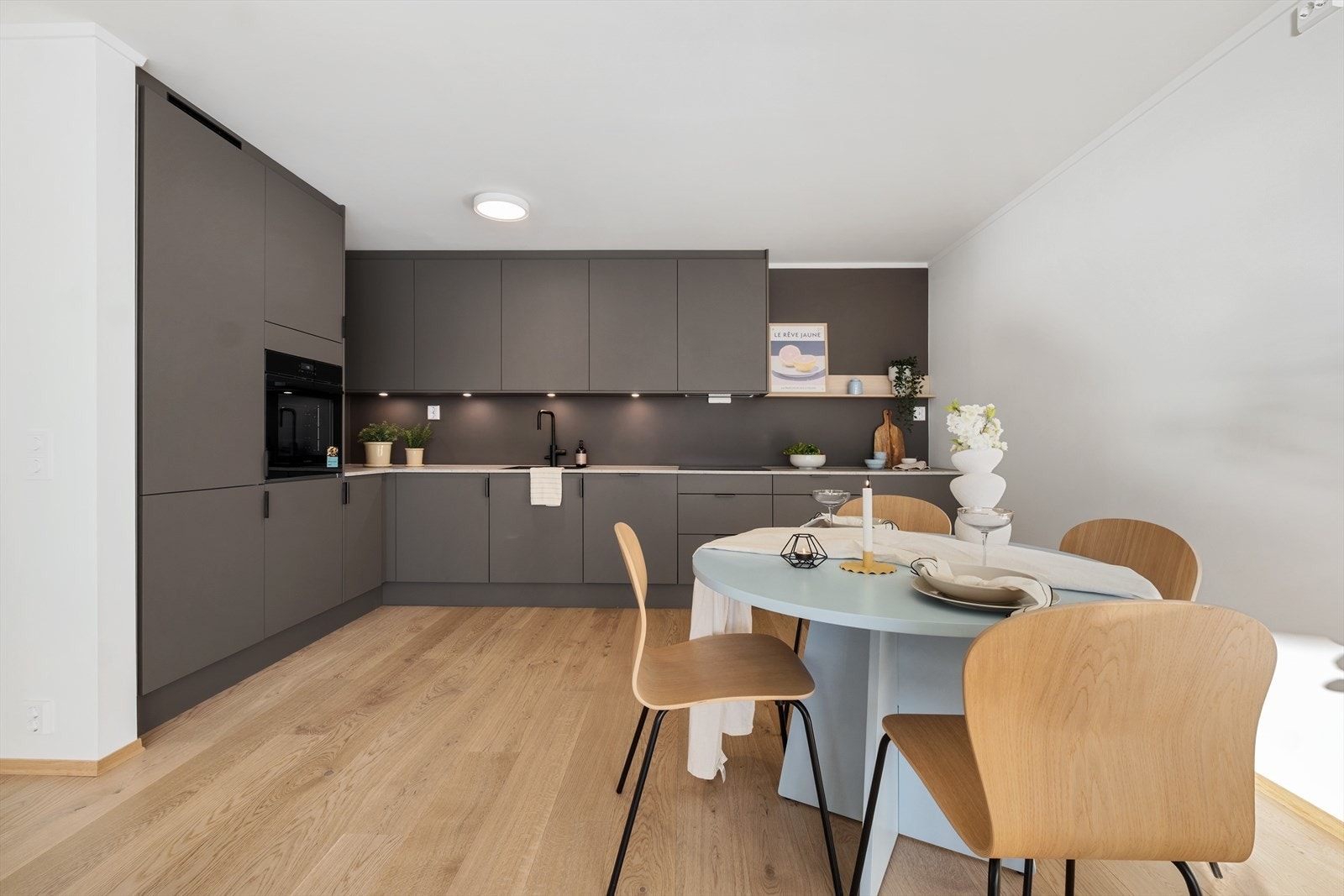 Kjøkkenet ligger i åpen løsning mot stuen og fremstår moderne med slette fronter i en stilren grå utførelse Galleribilde