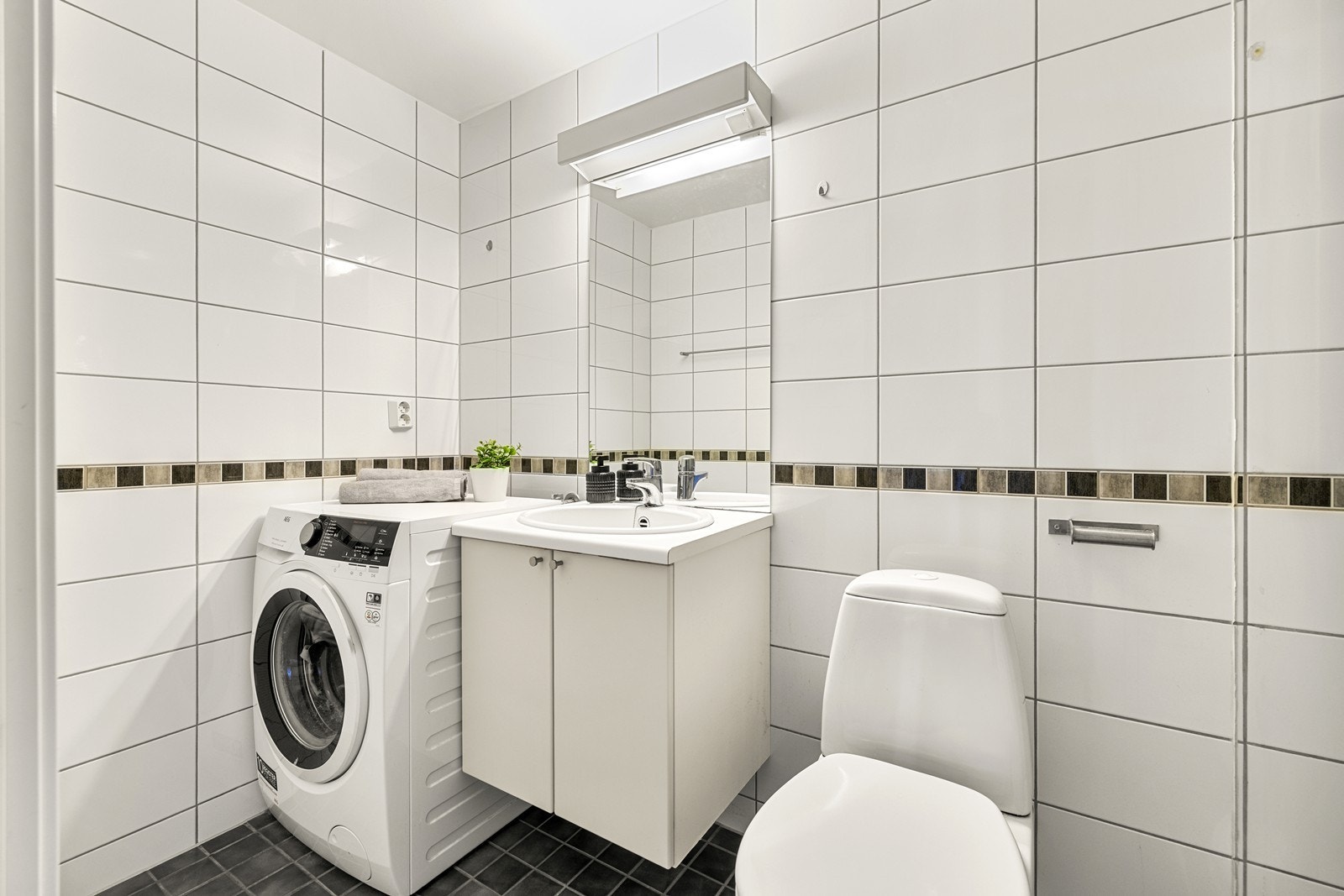 Badet har flislagt gulv med elektriske varmekabler og vegger med fliser. Det er opplegg for vaskemaskin. Galleribilde