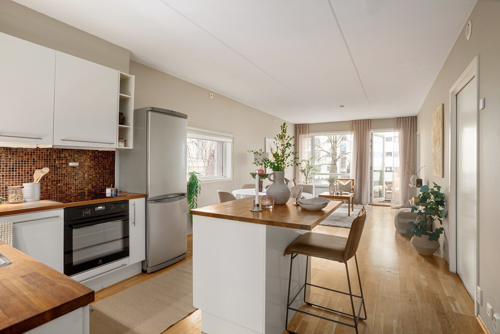 Lyst og pent kjøkken med øy, glatte fronter og god skap- og benkeplass Galleribilde