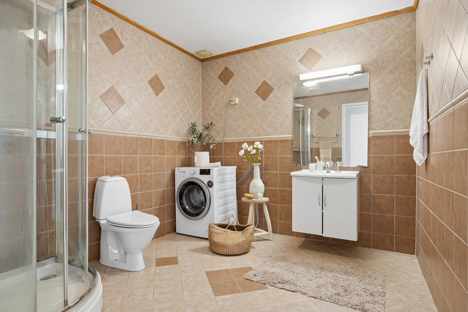 Romslig helfliset bad/vaskerom med gulvvarme som gir en behagelig temperatur. Rommet er utstyrt med nedfelt servant, toalett, dusjkabinett og opplegg for vaskemaskin. Mekanisk avtrekk. Galleribilde