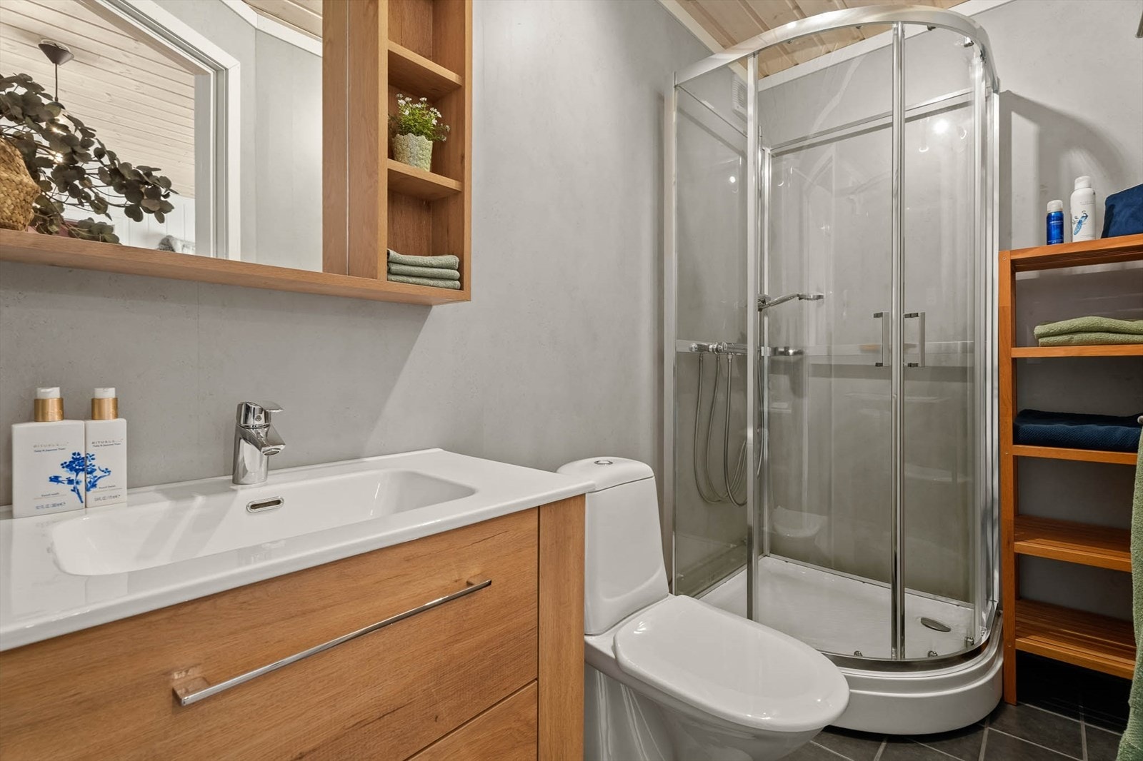 Bad har flis på gulv og baderomsplater på vegger. Her er det dusjkabinett, toalett og innredning med heldekkende hvit vask, underskuffer med slette fronter og speil. Det er varmekabler i gulv og elektrisk styrt vifte. Galleribilde