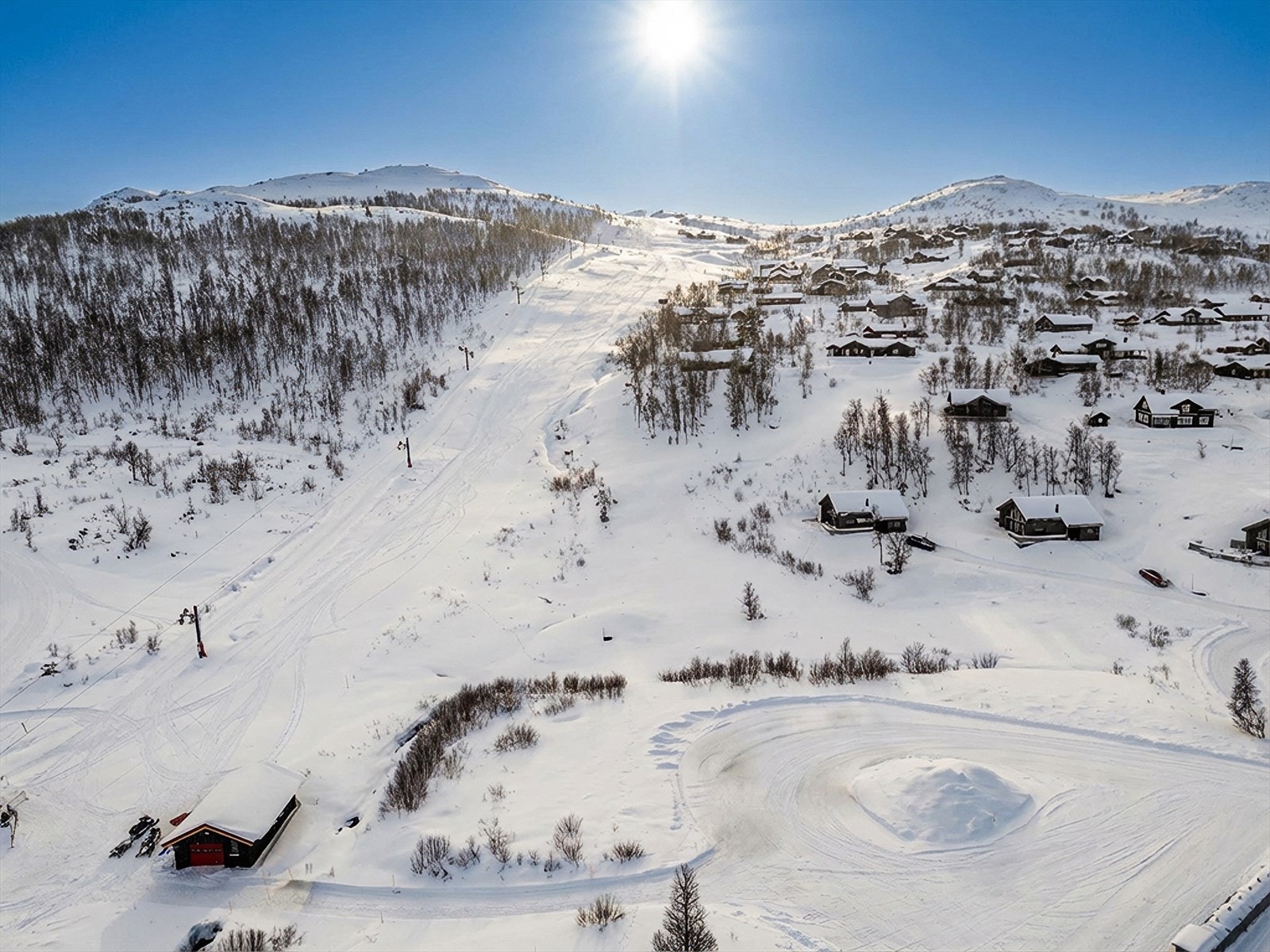 Hytta har to aksjer i skitrekket som medfølger hytta ved salg, og betaler da kun kr. 500,- pr år for fri bruk for hele familien i trekket bakenfor hytta. Bildet er tatt i overskyet vær, og himmel og lys er justert ved hjelp av KI. Galleribilde