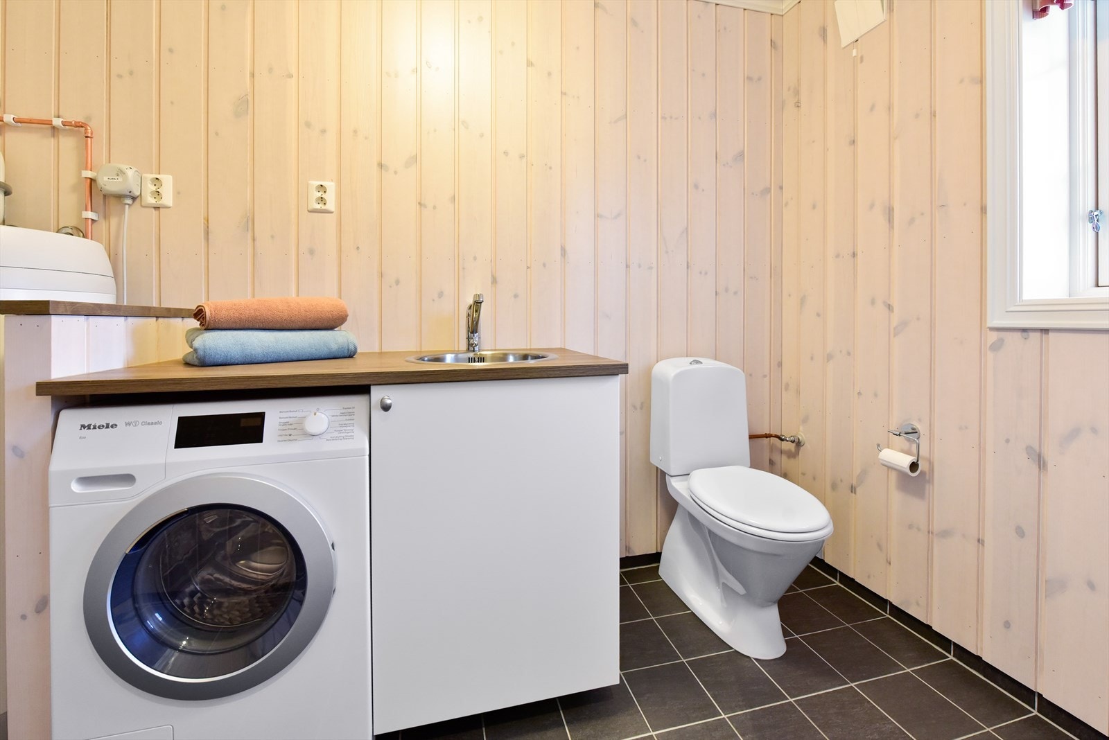 Praktisk vaskerom med opplegg for vaskemaskin, servant, et ekstra toalett og varme i gulvet. Galleribilde