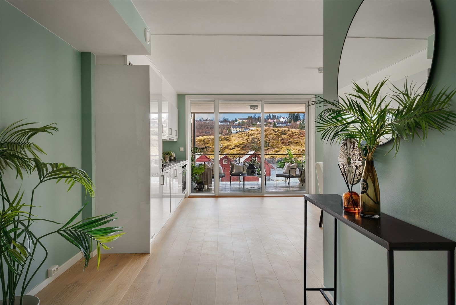 Fra gangen åpner leiligheten seg opp mot stuen og kjøkkenet, med direkte siktlinje mot verandaen. Galleribilde