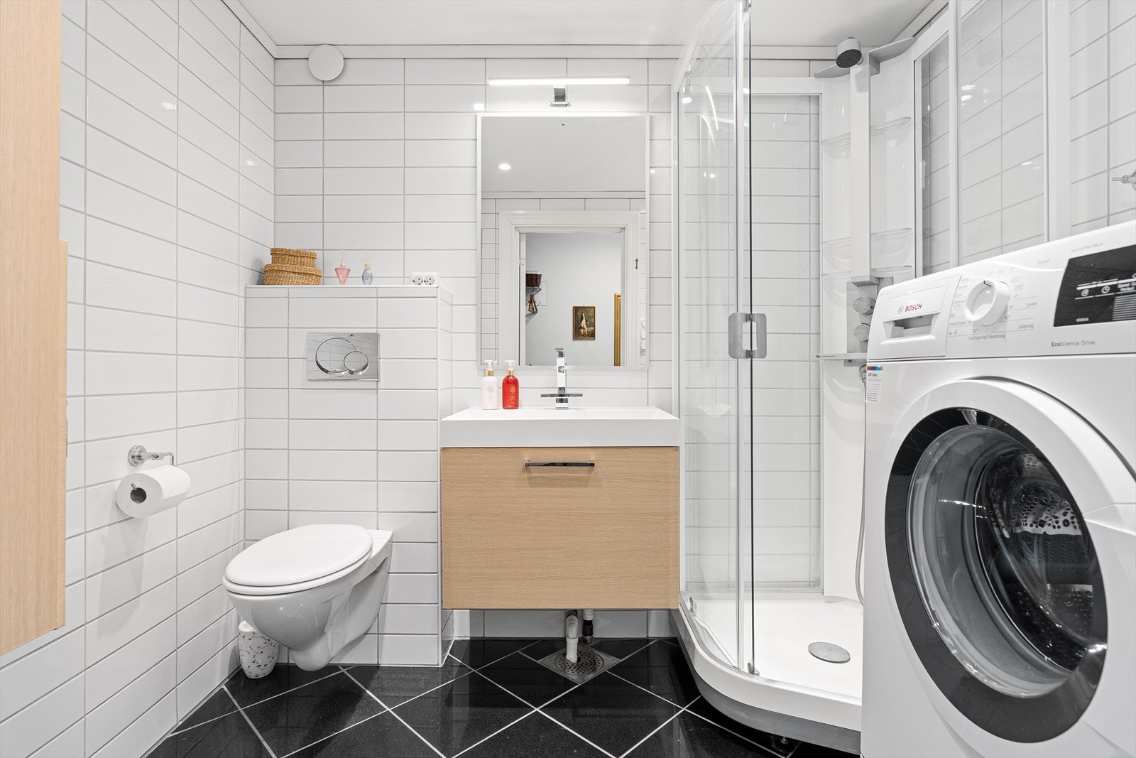 Badet er helfliset med varme i gulvet og ble pusset opp av tidligere eier i ca 2006. Det inneholder et vegghengt toalett, baderomsinnredning med speil over, dusjkabinett, samt plass og opplegg for vaskemaskin. Galleribilde