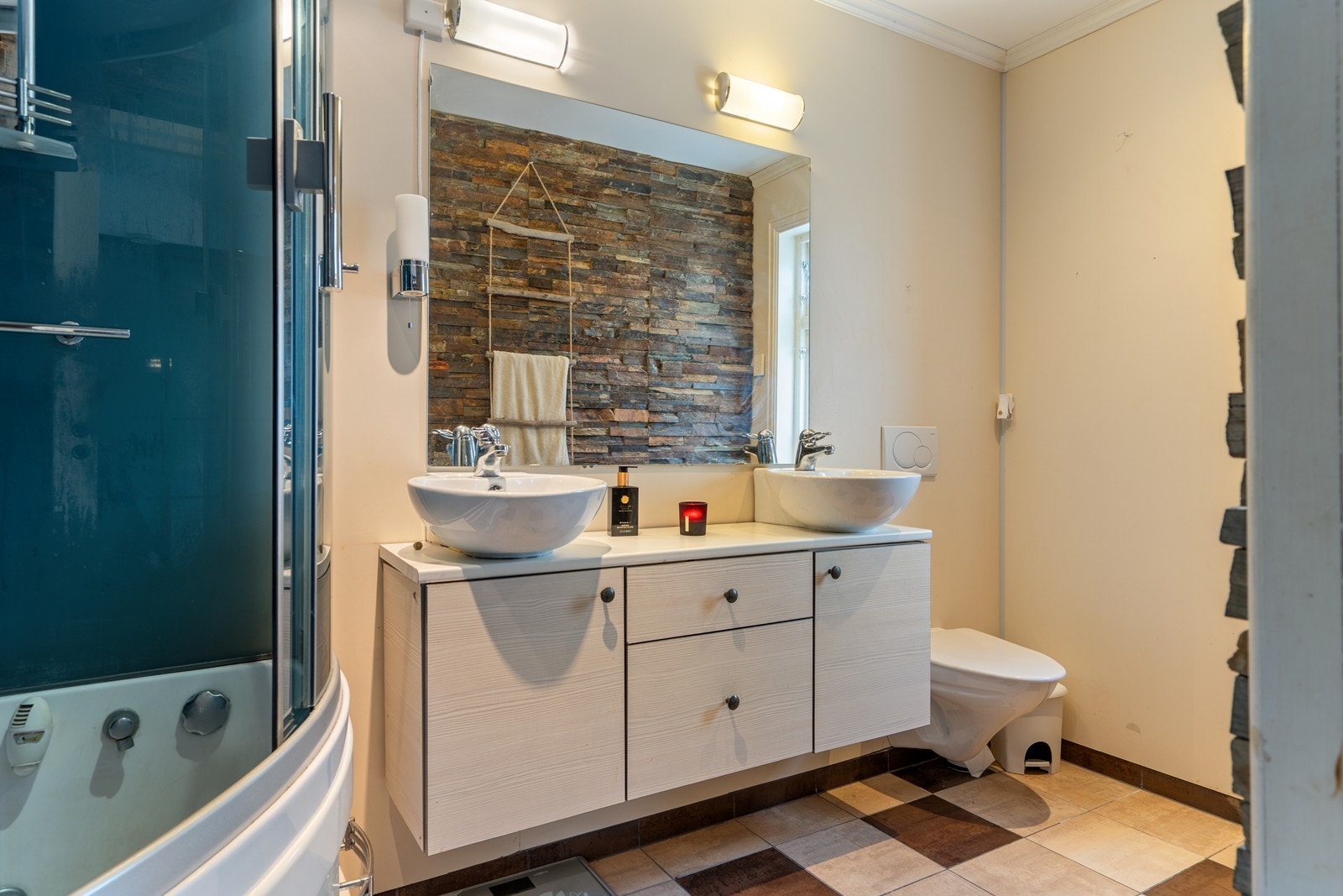 Baderom som har innredning med to påliggende servanter, veggmontert toalett og steamdusj med badekar Galleribilde