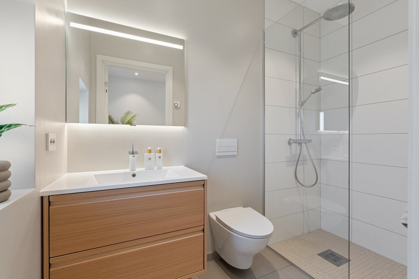 Baderommet i 2. etasje har fliser på gulv og i dusjsonen. Badet er innredet med vegghengt toalett, dusjhjørne med glassvegg, samt baderomsinnredning med servant og speil. Galleribilde